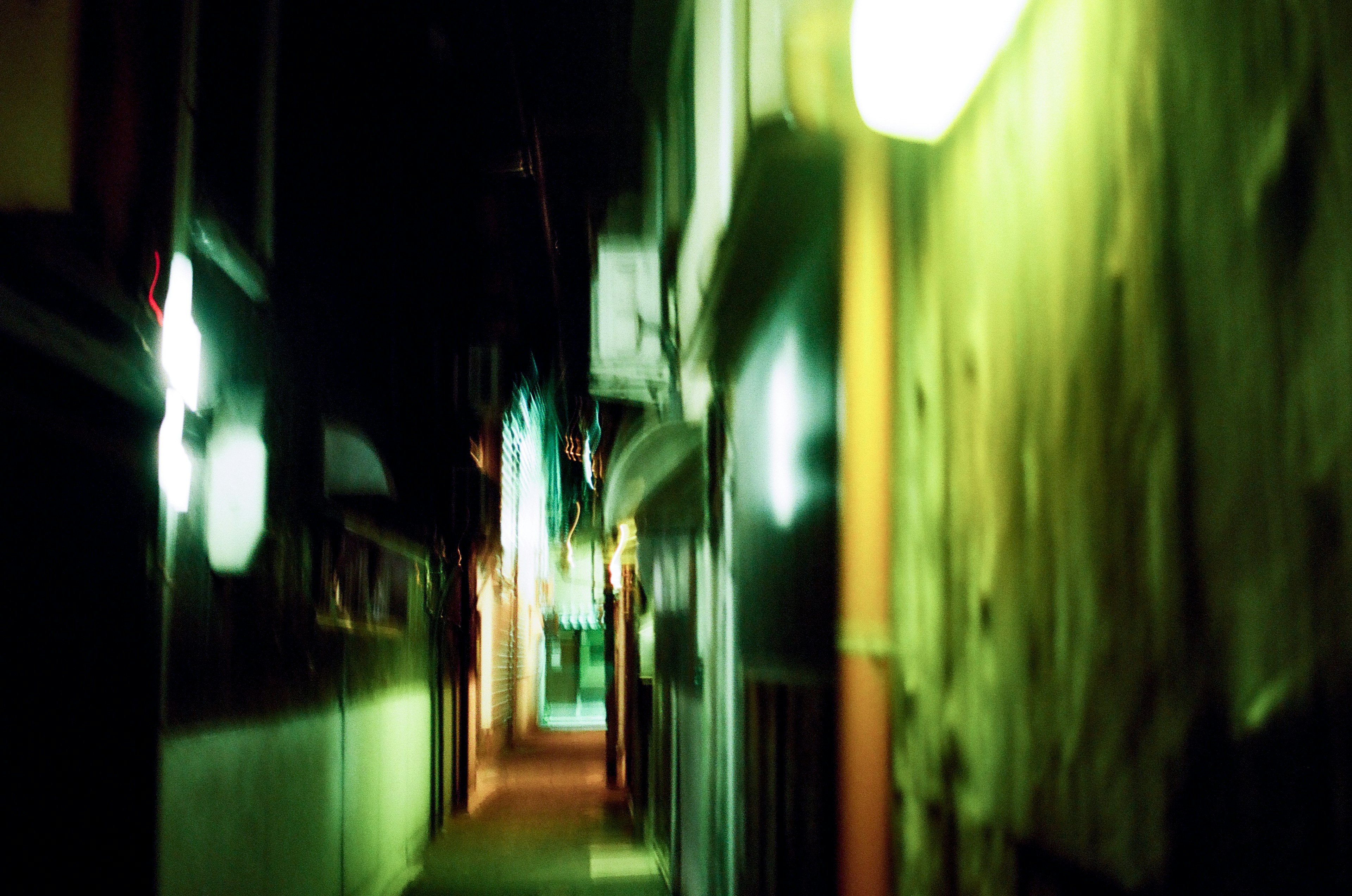 Eine enge Gasse, beleuchtet von grünen Lichtern, die eine geheimnisvolle Atmosphäre schafft