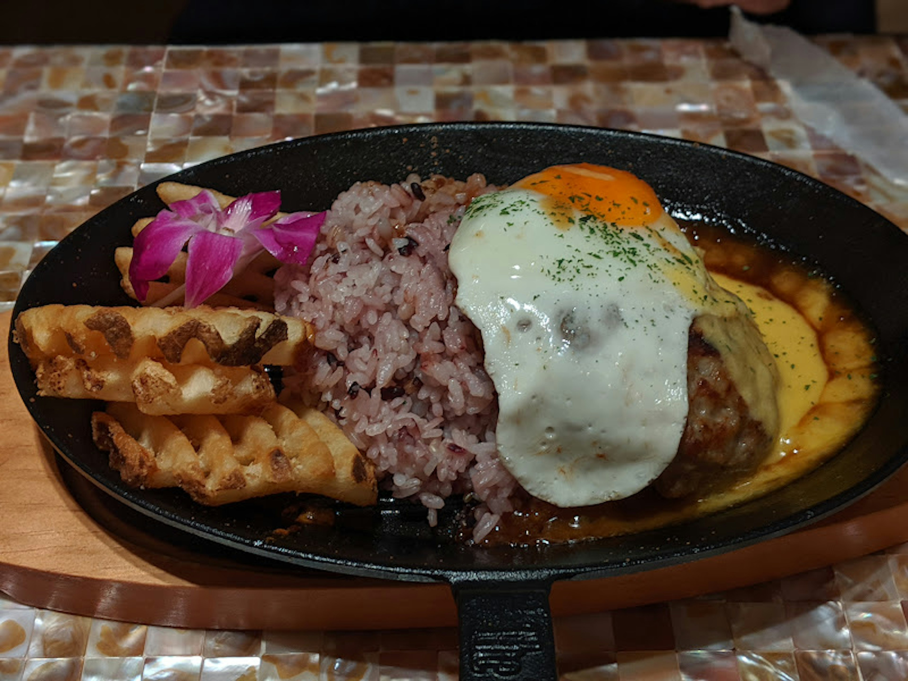 Bratpfanne mit Hamburgersteak und Spiegelei serviert mit lila Reis und Waffeln