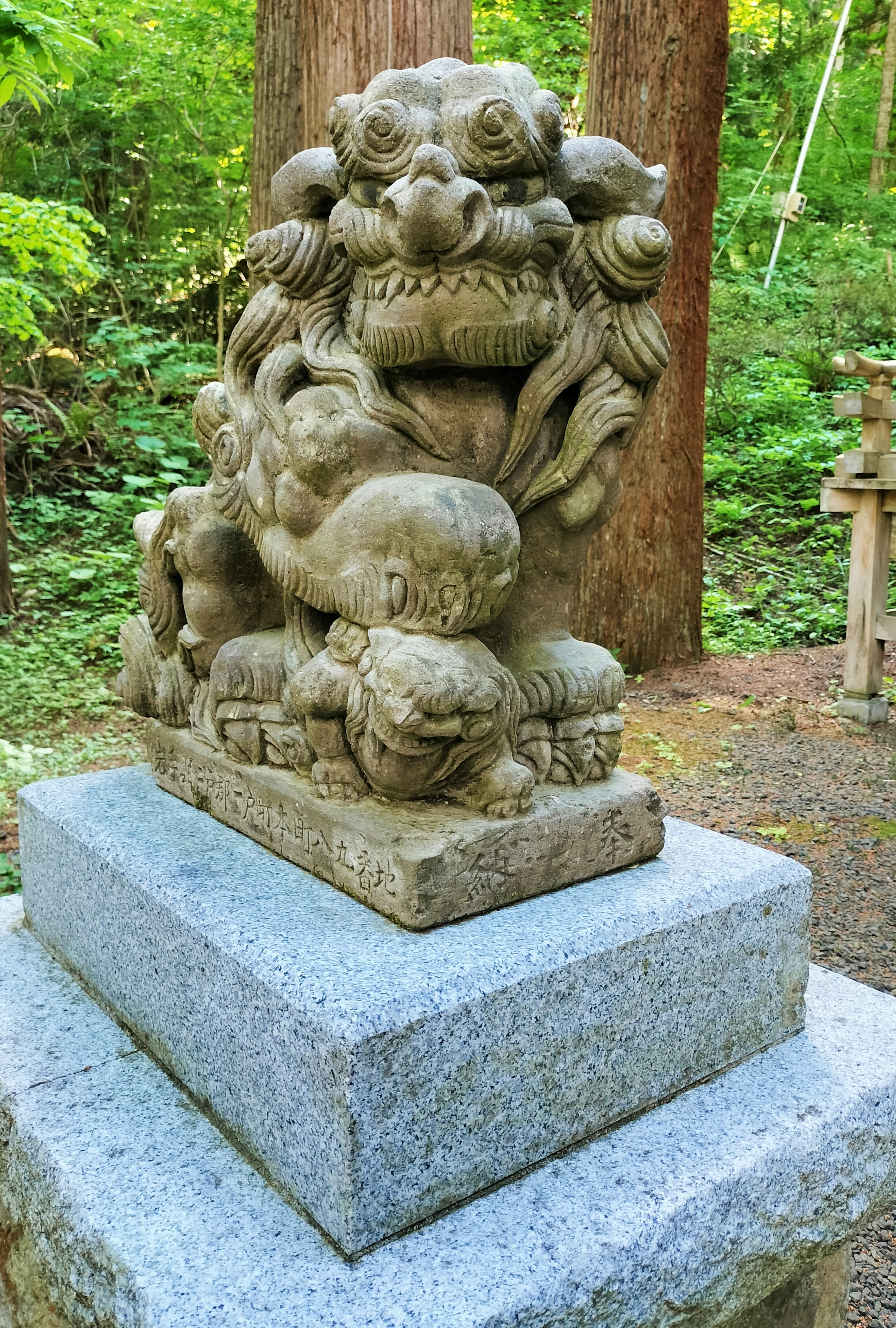 Stone lion sculpture surrounded by green trees