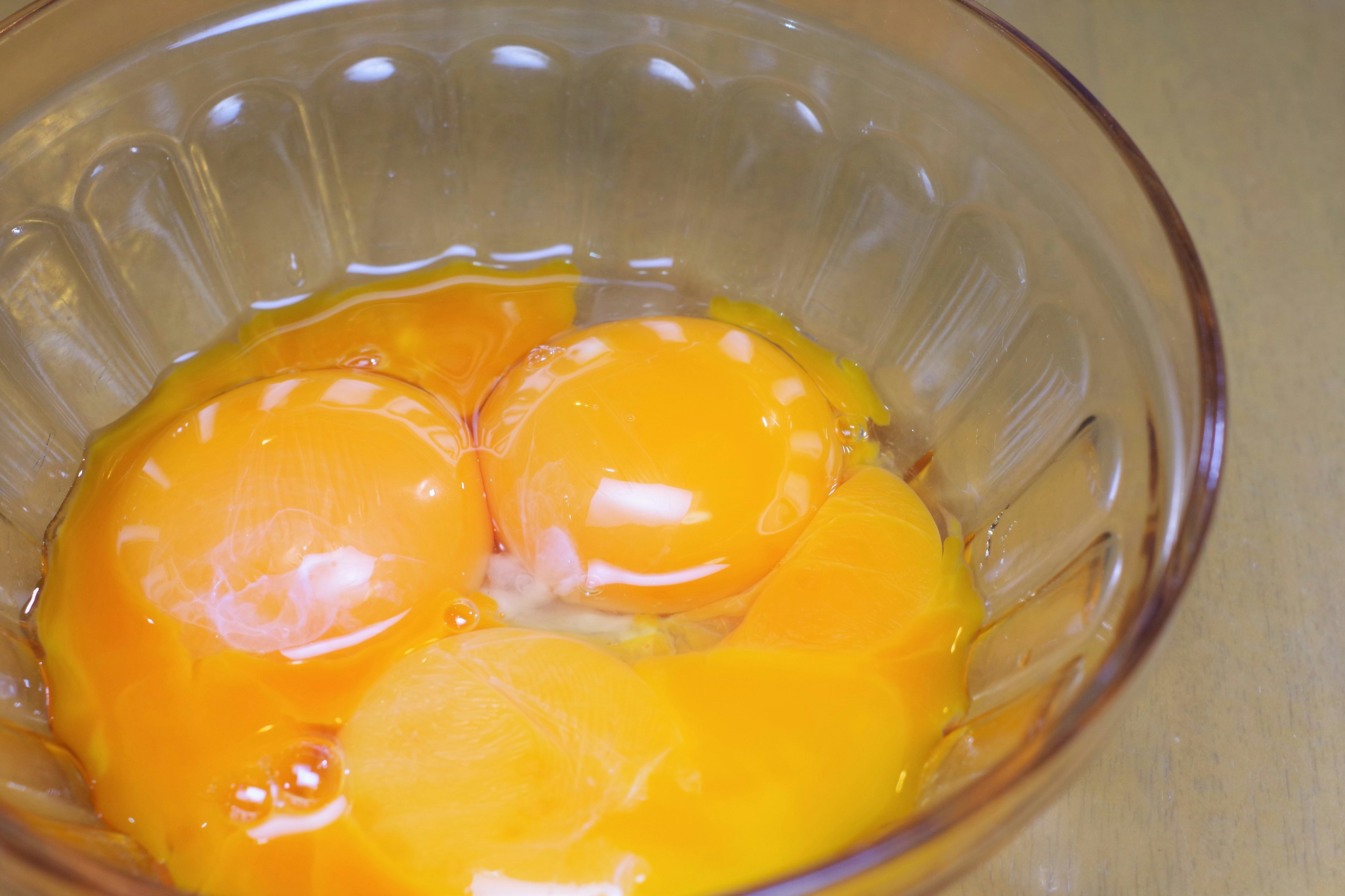 Three fresh egg yolks in a clear bowl