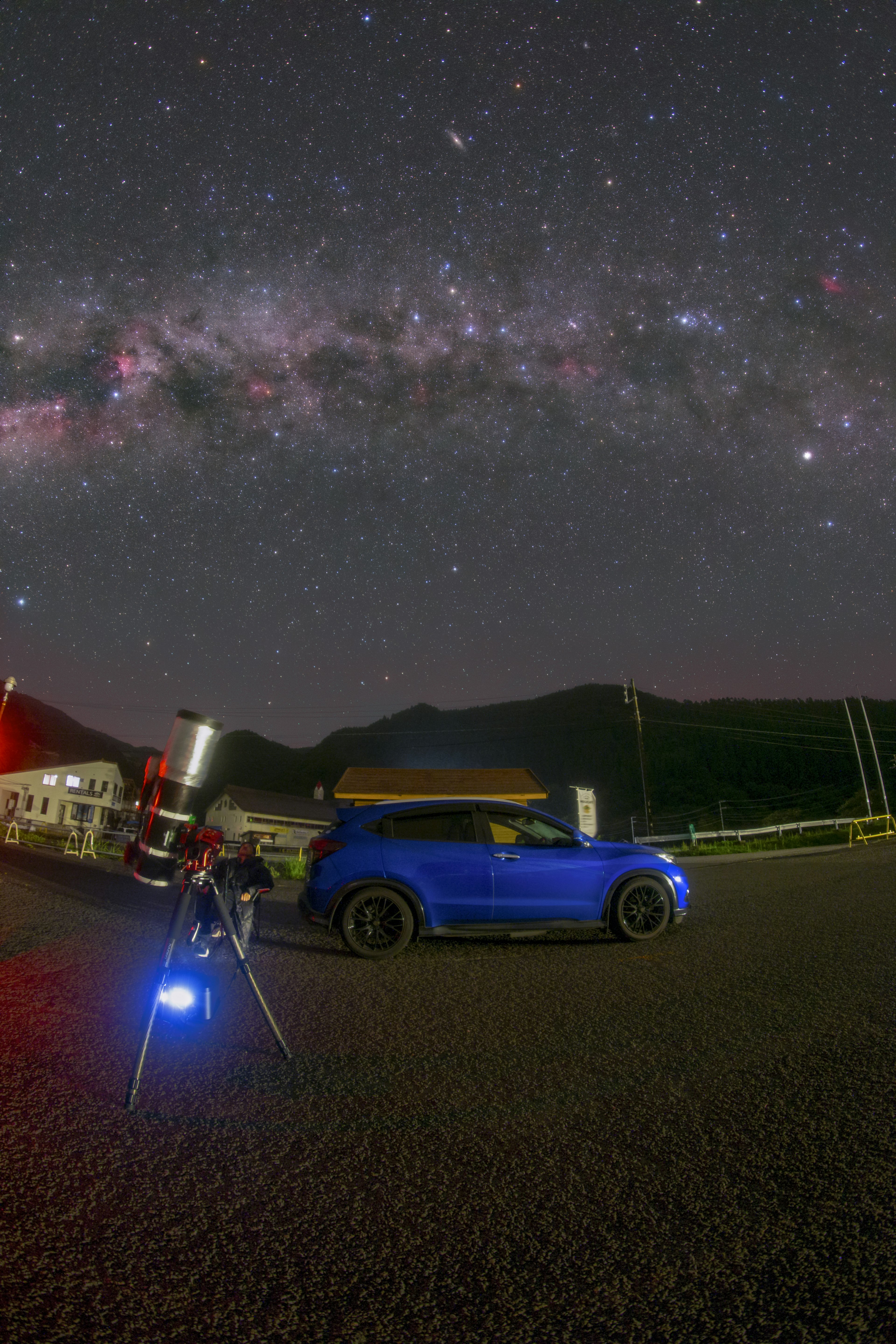 星空の下に青い車と望遠鏡がある風景