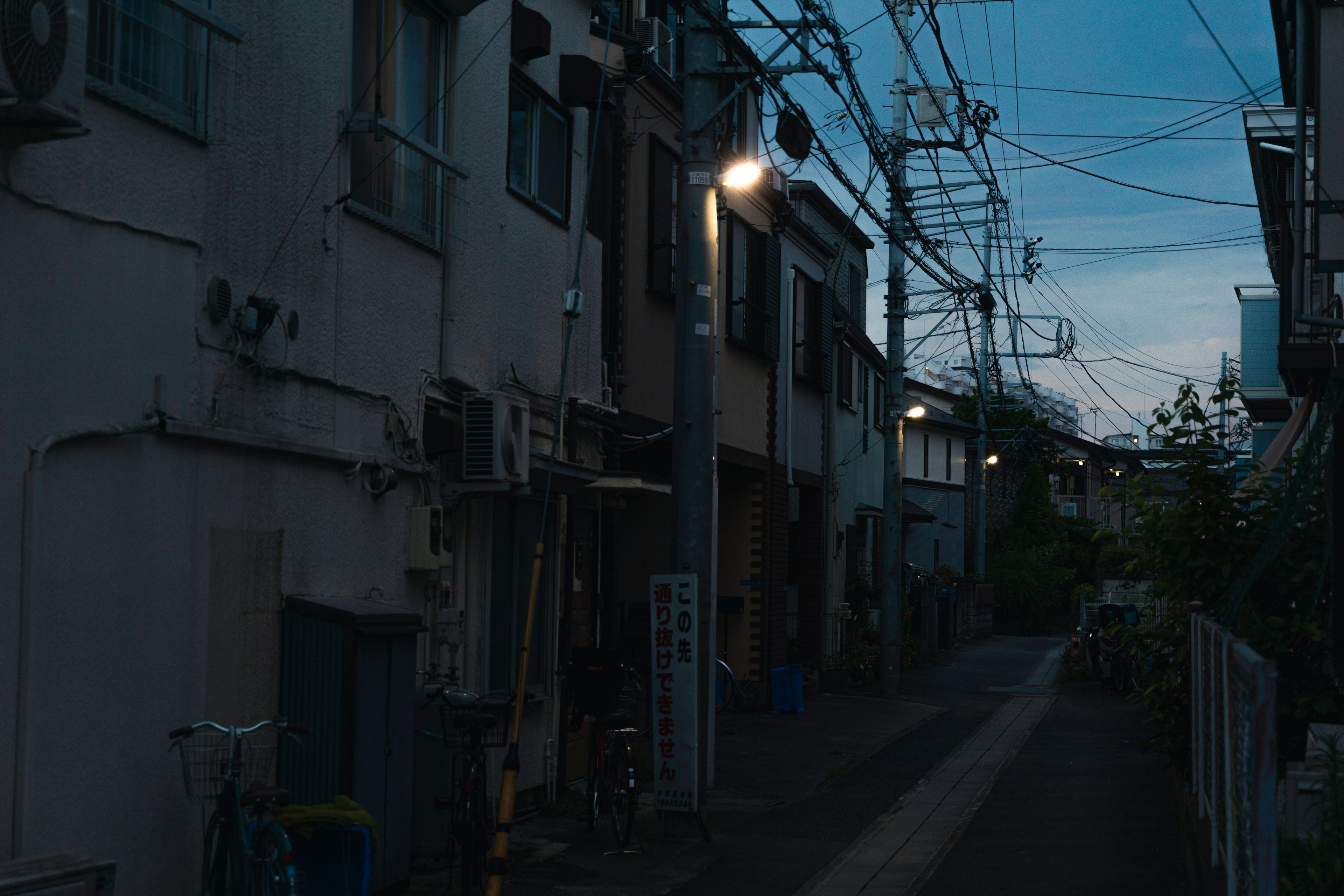 薄暗い路地に沿った建物と電線が見える夜の風景