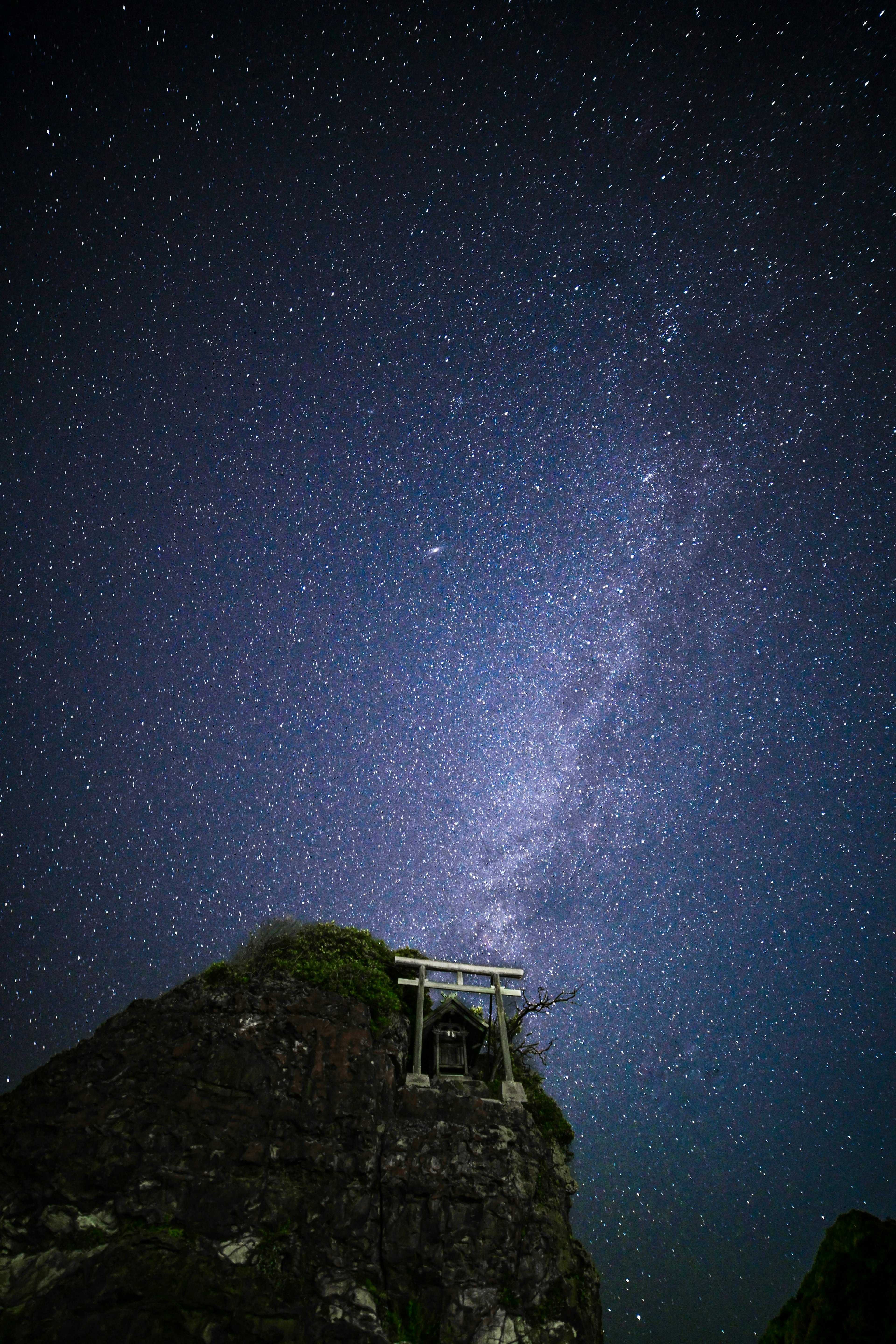 Paysage montagneux rocheux avec un torii sous un ciel étoilé