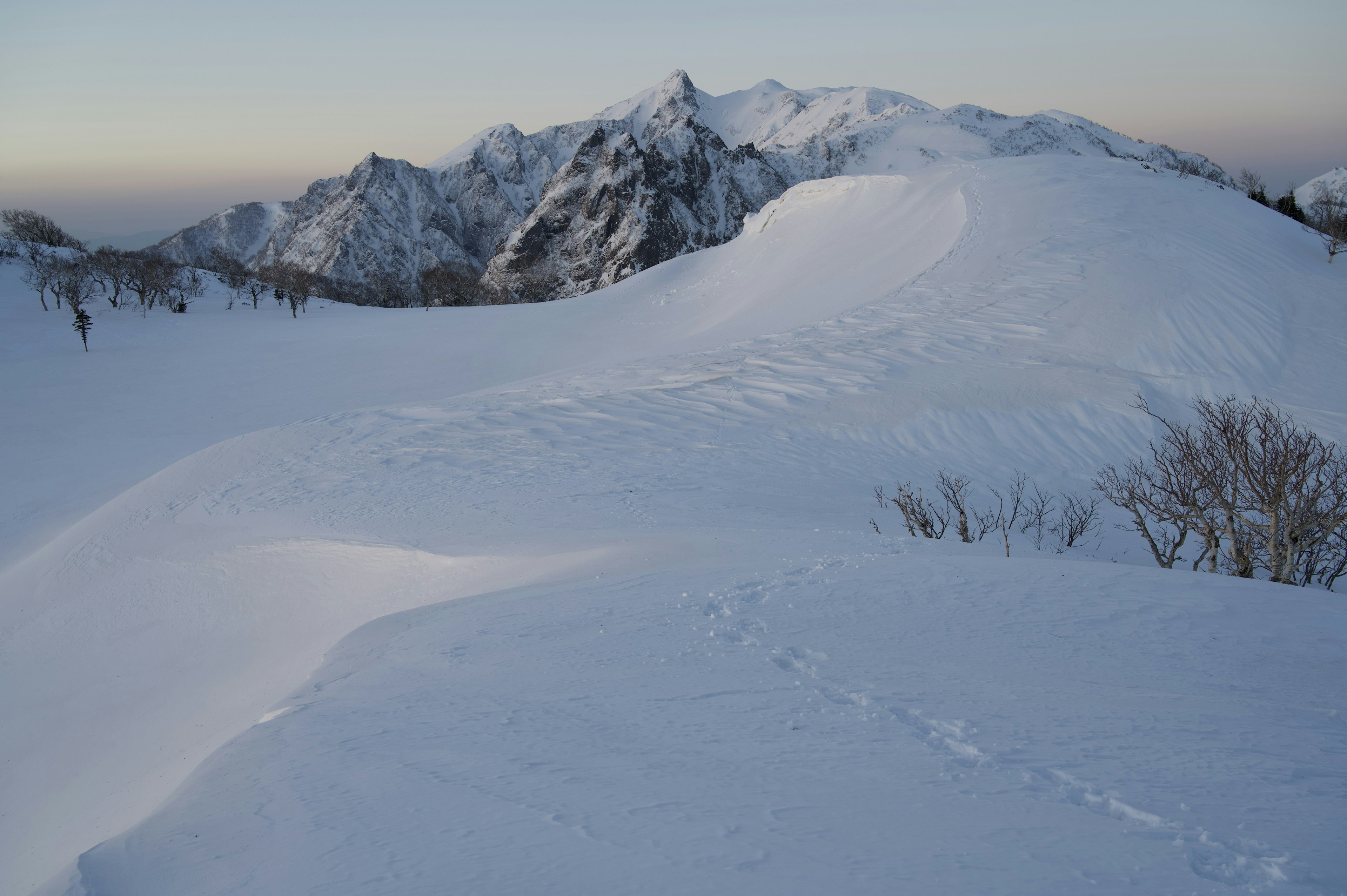 被雪覆蓋的山脈景觀，平滑的坡面和遙遠的山峰