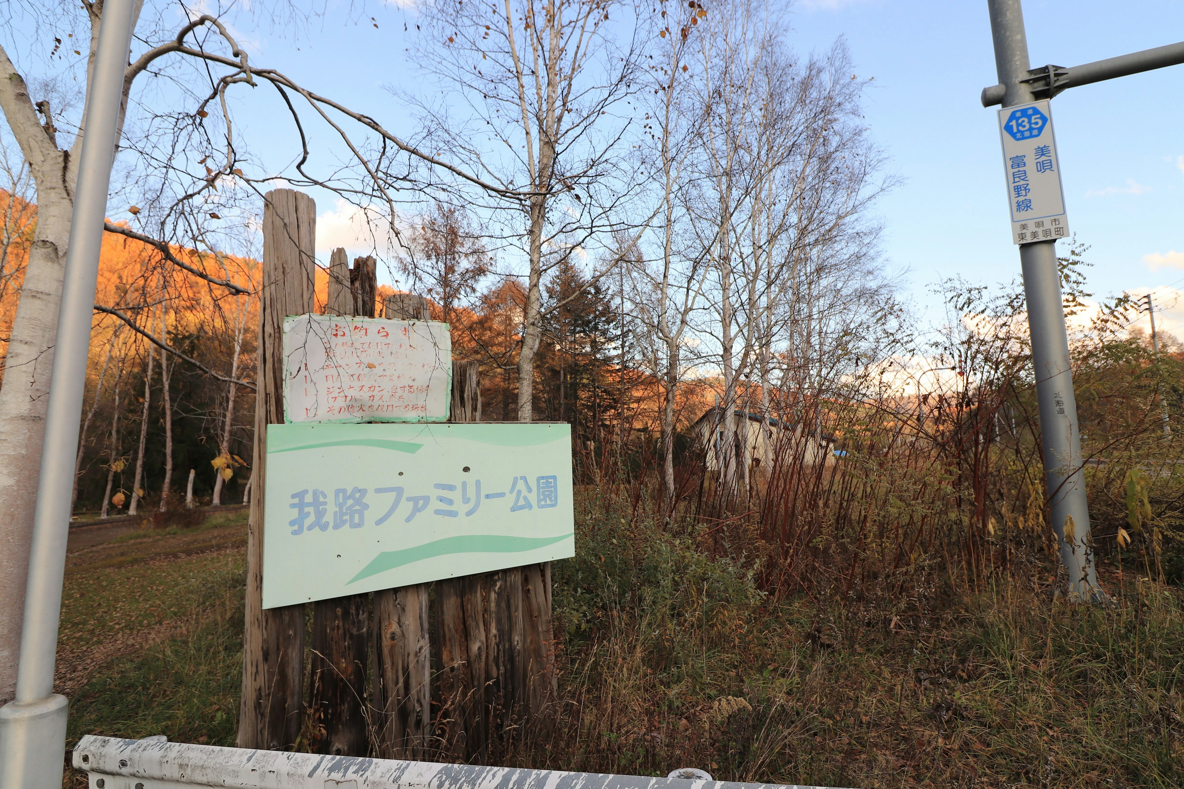 A wooden sign surrounded by natural scenery featuring autumn foliage