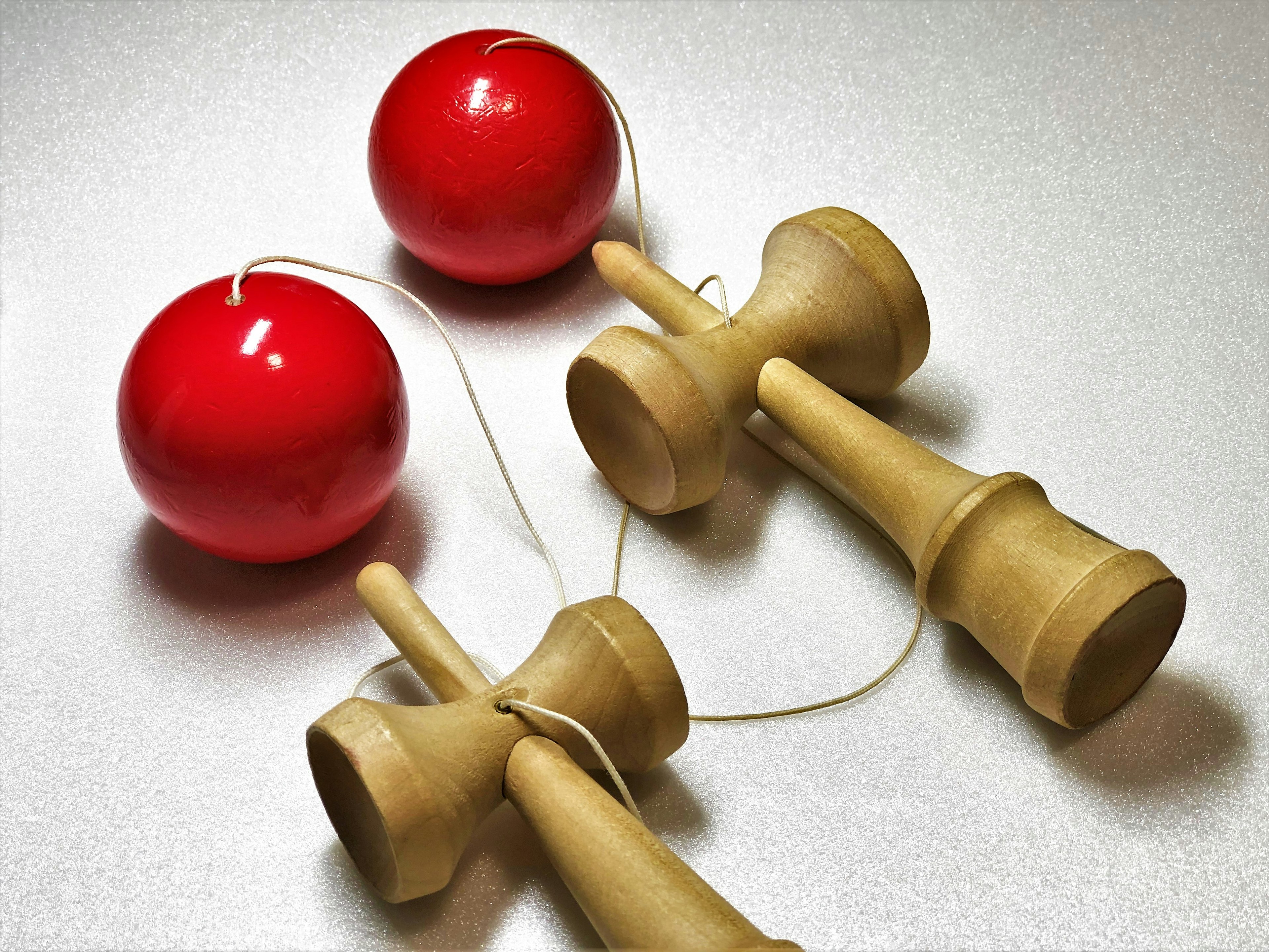 Traditionelles Kendama mit roten Bällen und Holzgriffen