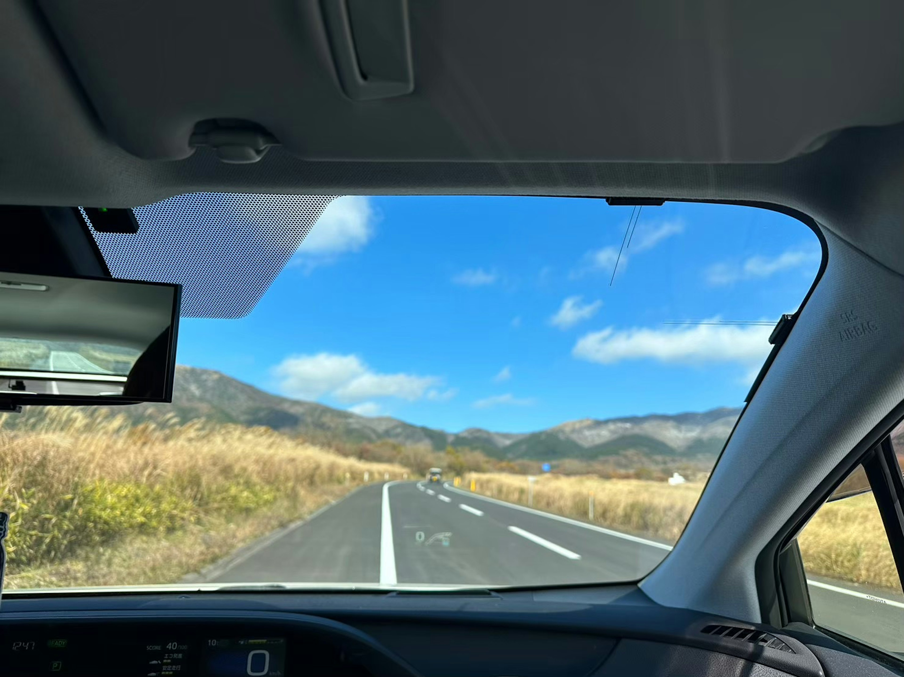 Pemandangan langit biru dan pegunungan dari dalam mobil