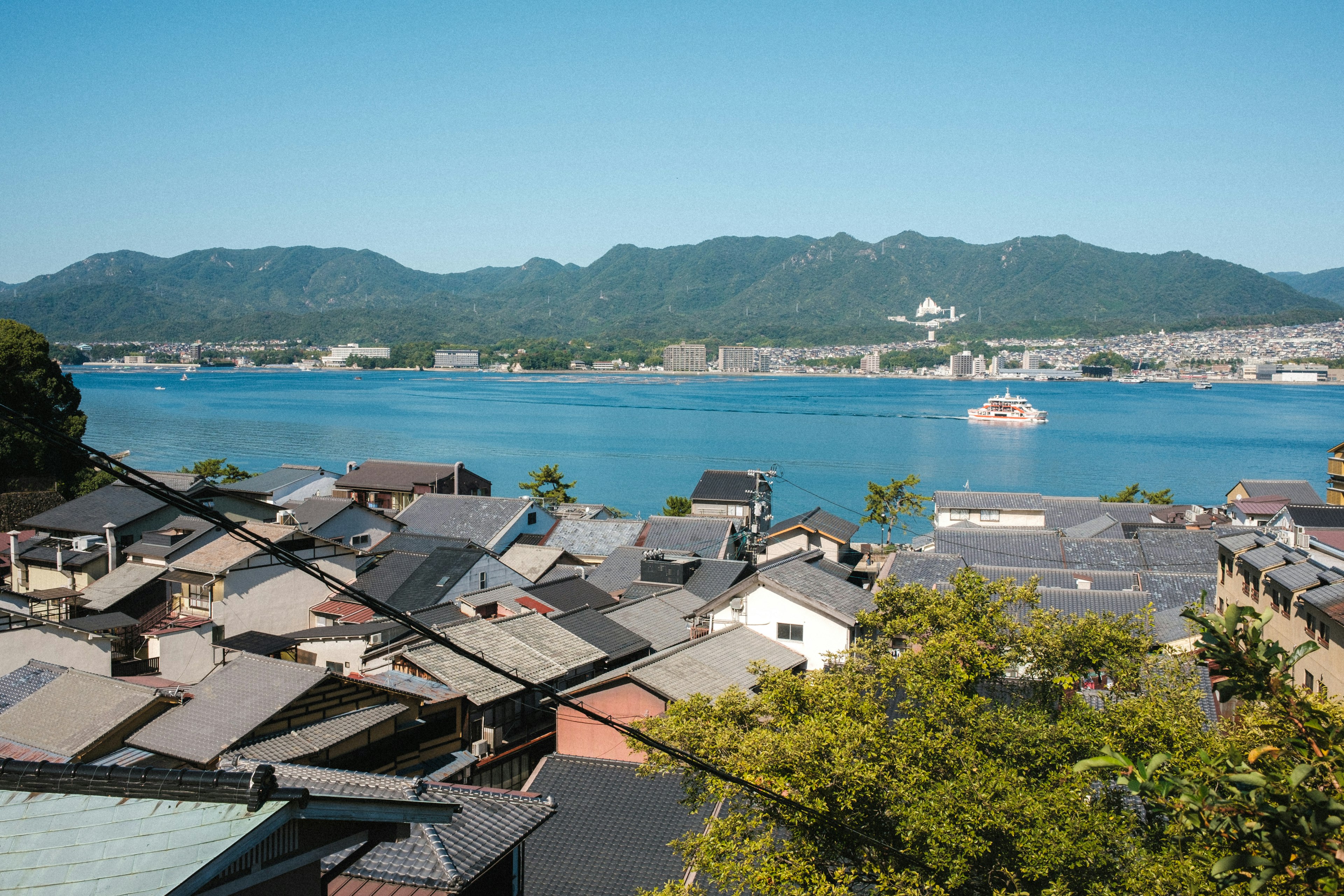 Scenic view of a coastal town surrounded by mountains and water with clear blue skies