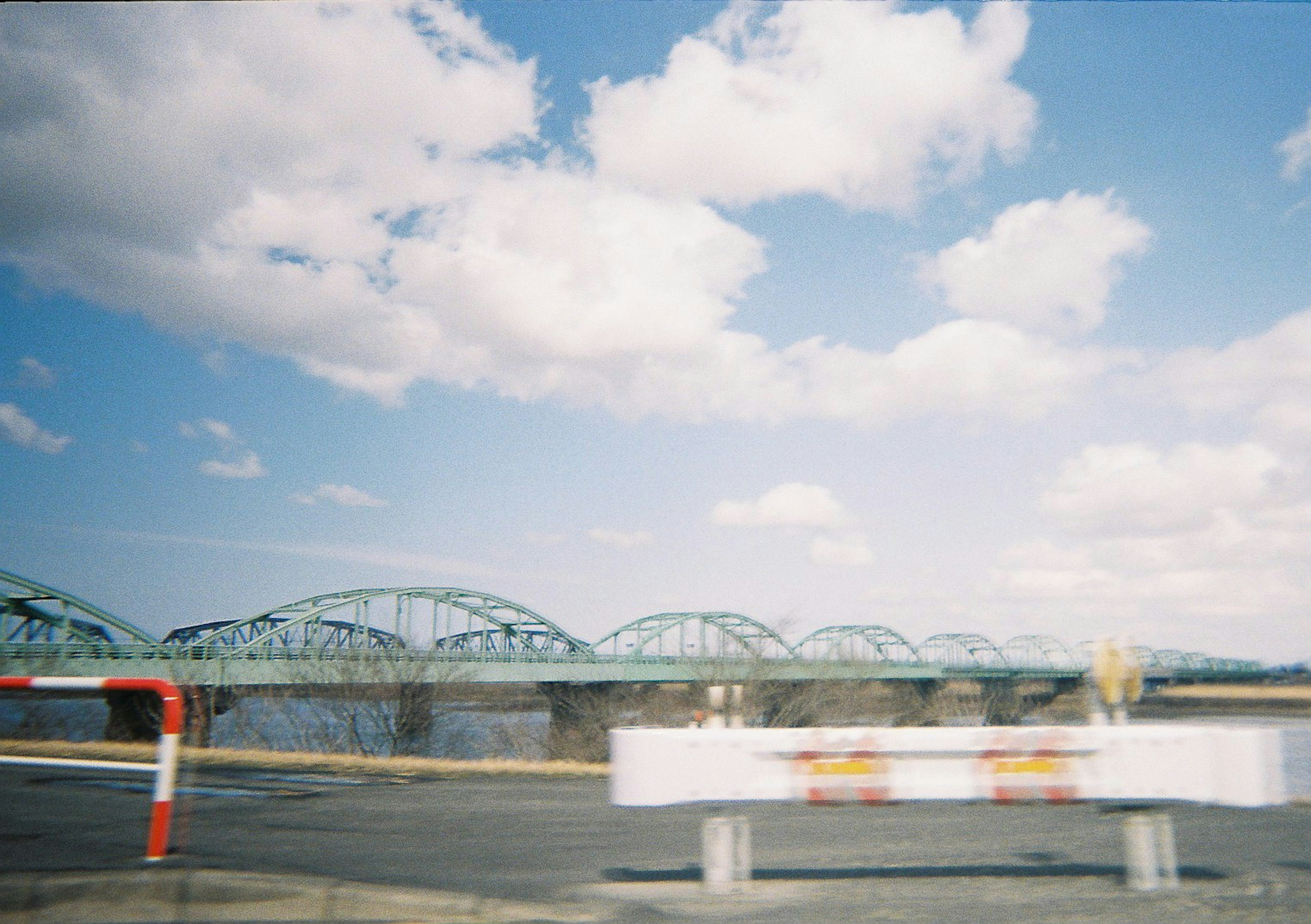 Une vue pittoresque d'un pont en arc vert sous un ciel bleu avec des nuages blancs duveteux