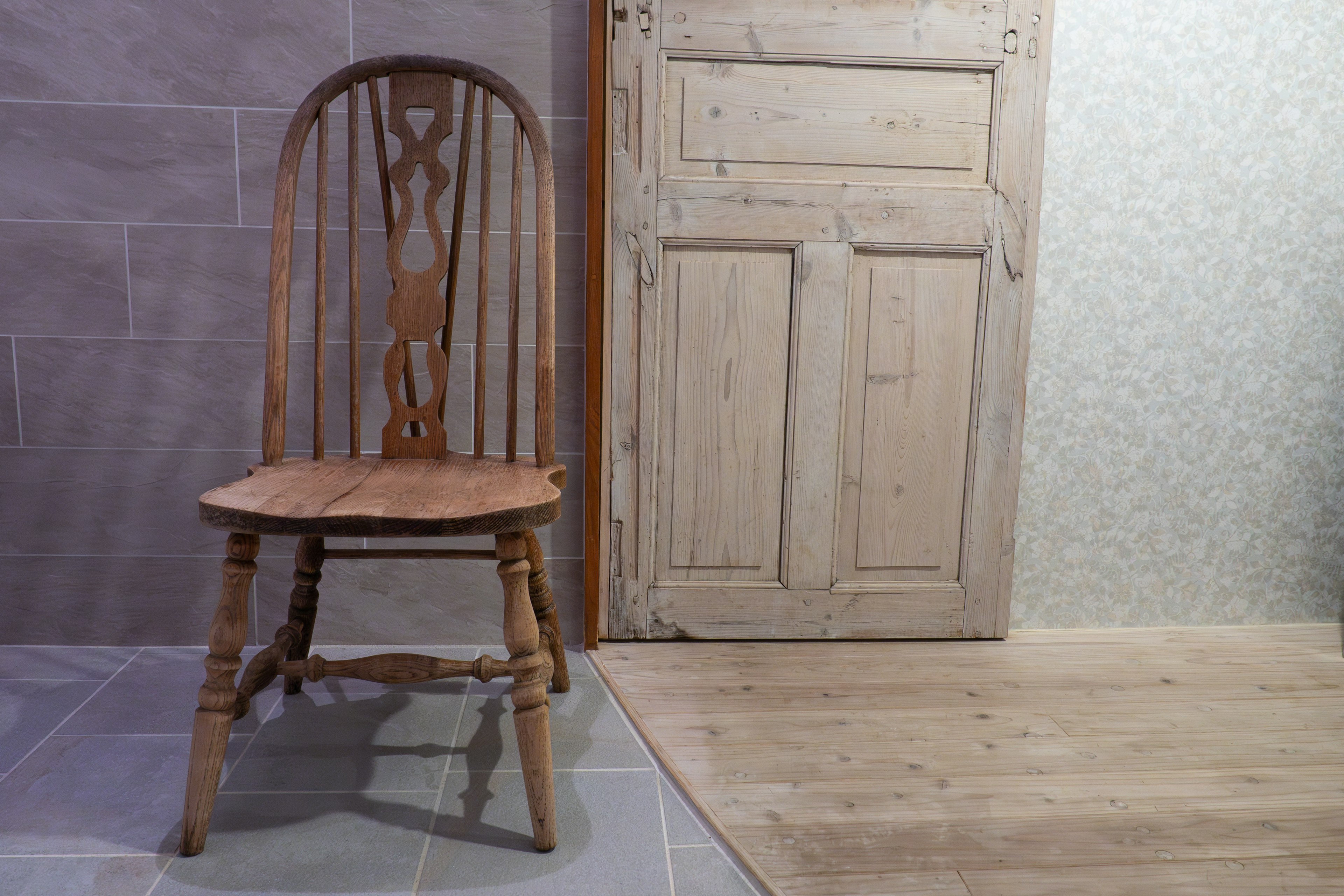 A wooden chair leaning against a wall in a simple indoor setting