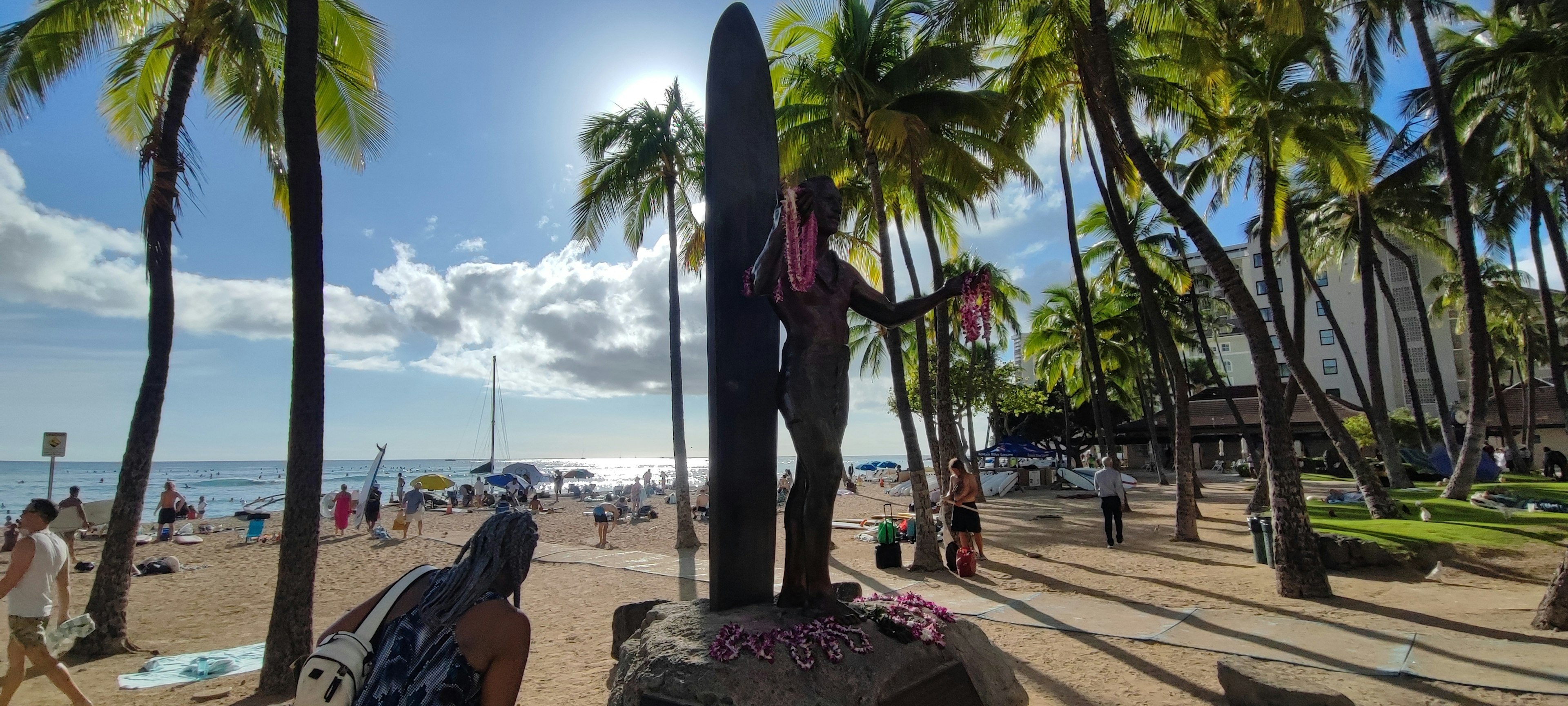 Surfstatue am Strand umgeben von Palmen