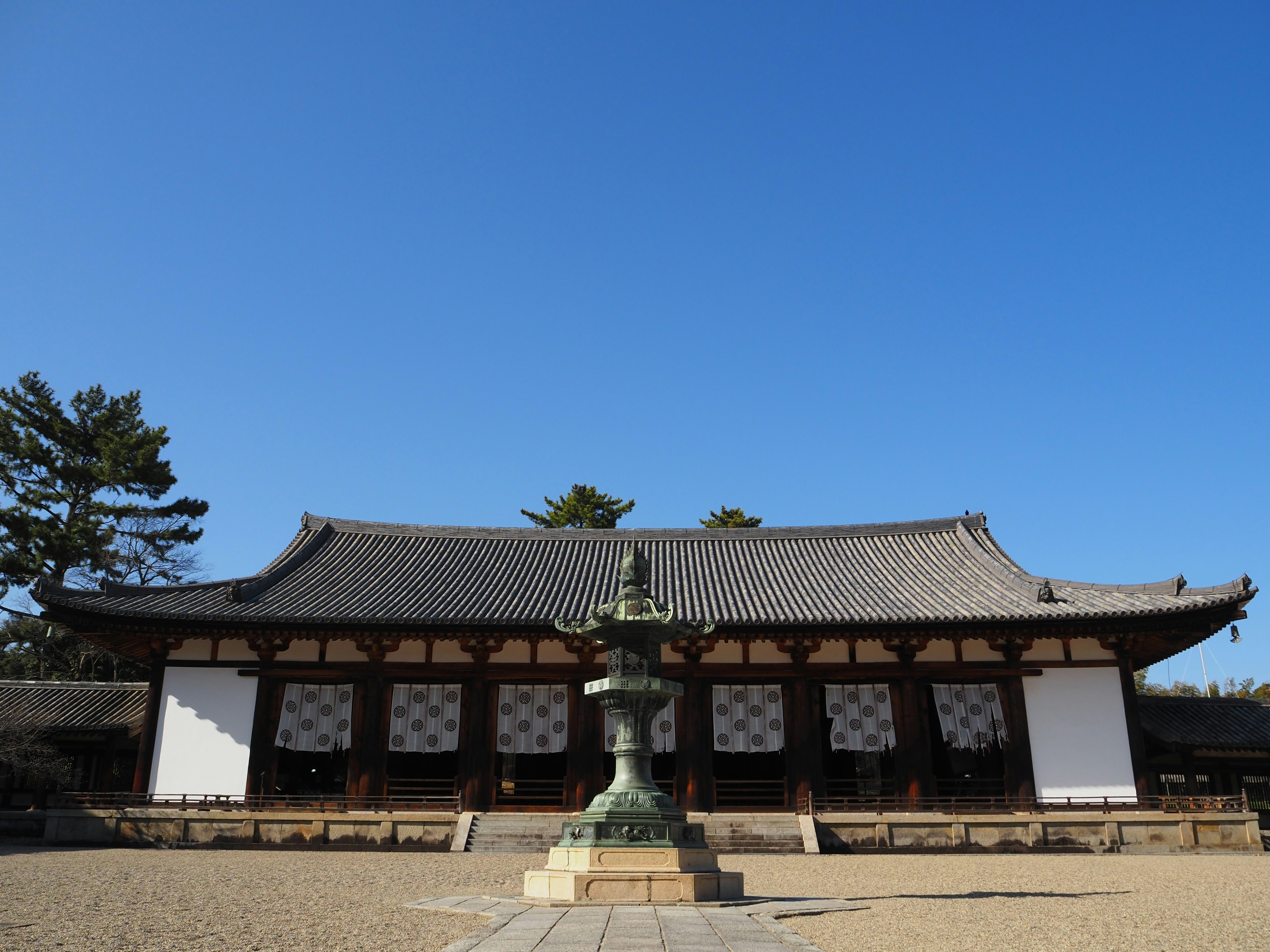 Traditional Japanese temple building under a clear blue sky with a central lantern