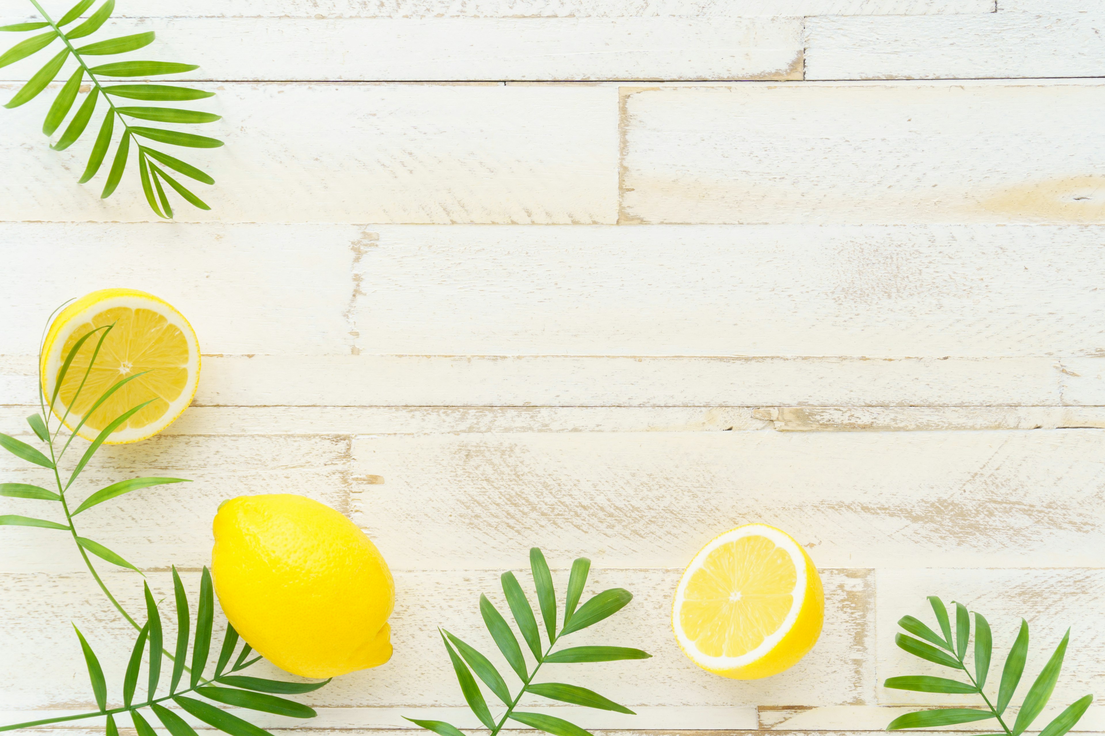 Lemons and green leaves arranged on a white wooden table