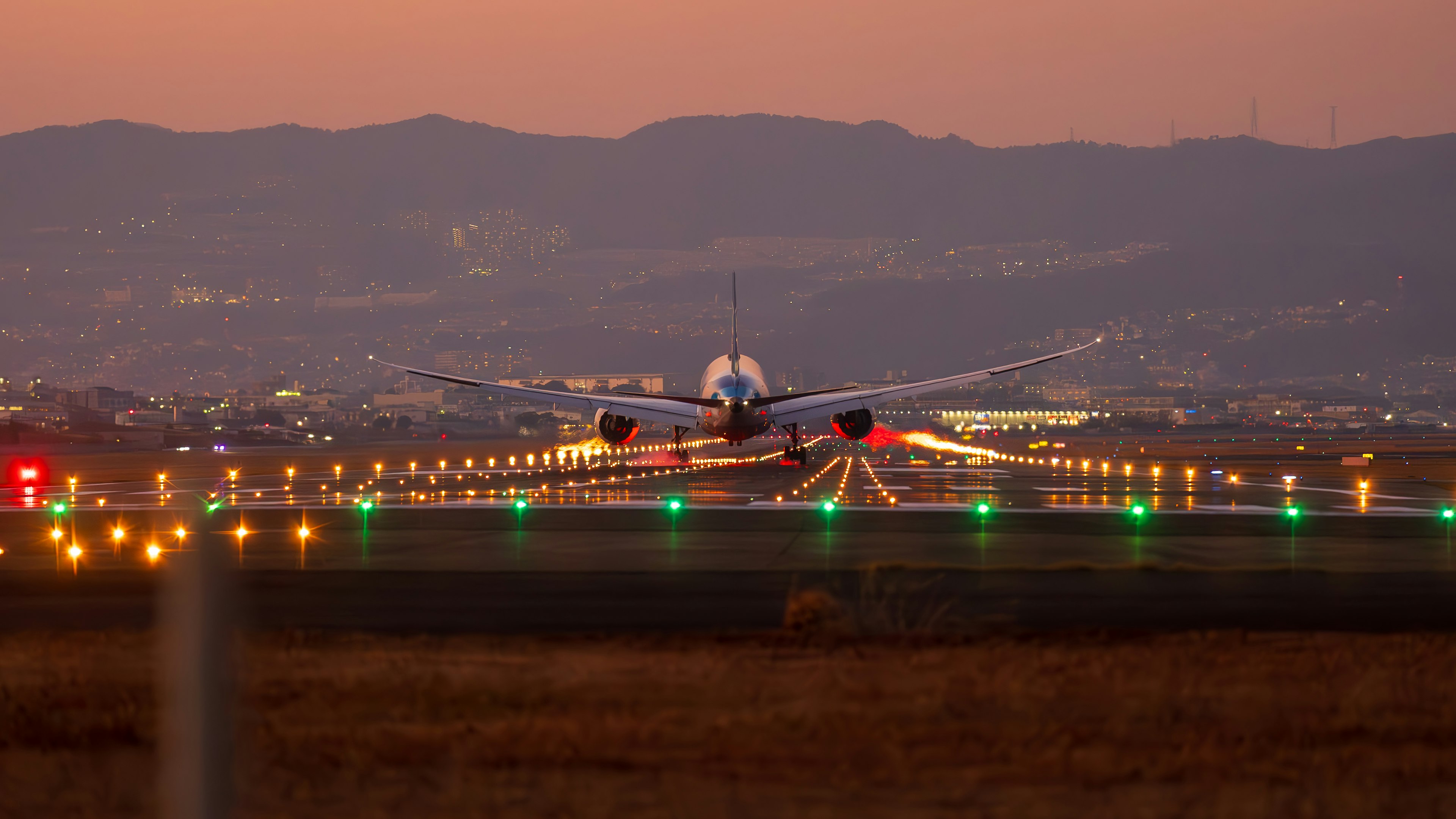 夕暮れ時の空港で滑走路に着陸する飛行機のシルエット