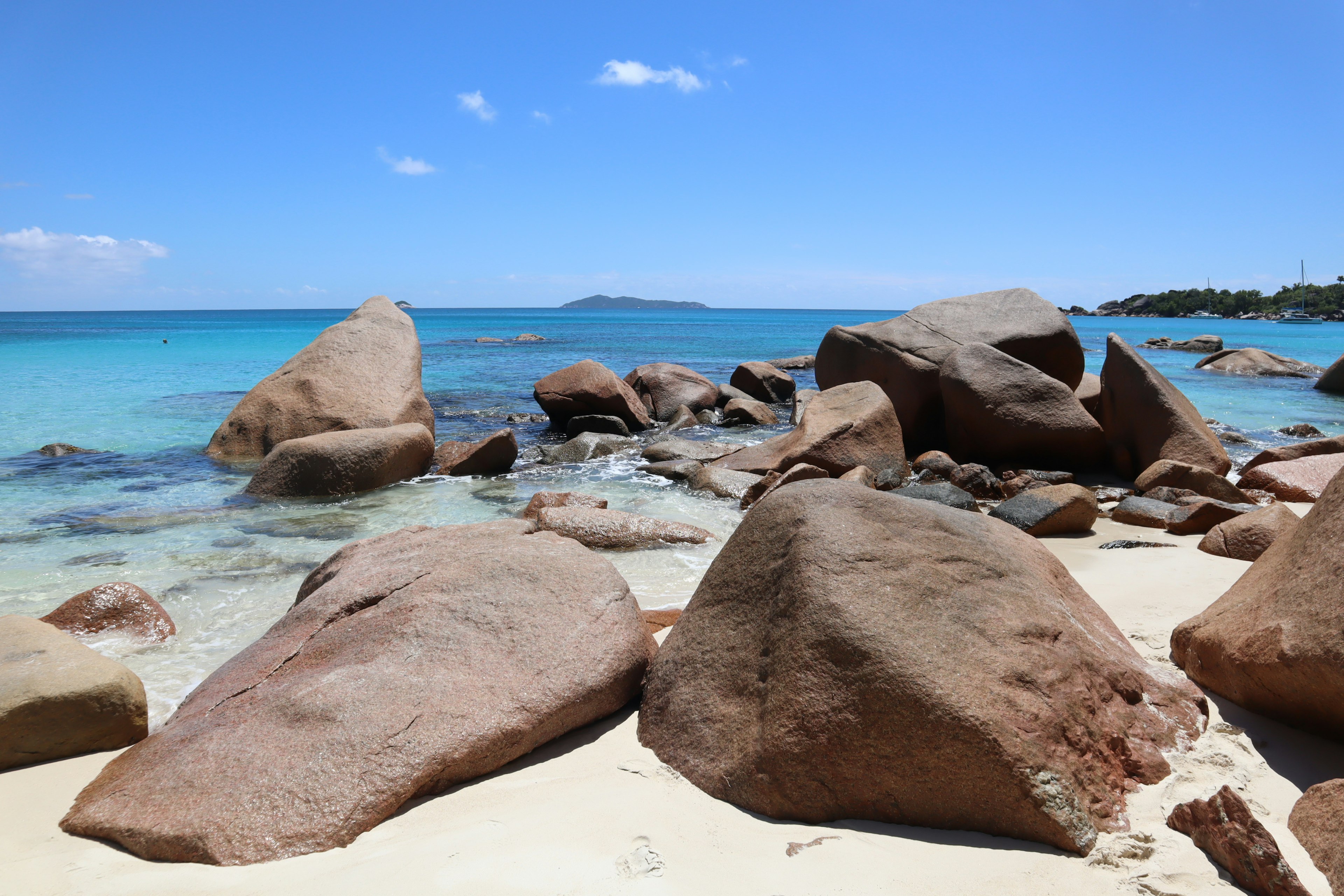 Escena de playa con grandes rocas y agua azul clara