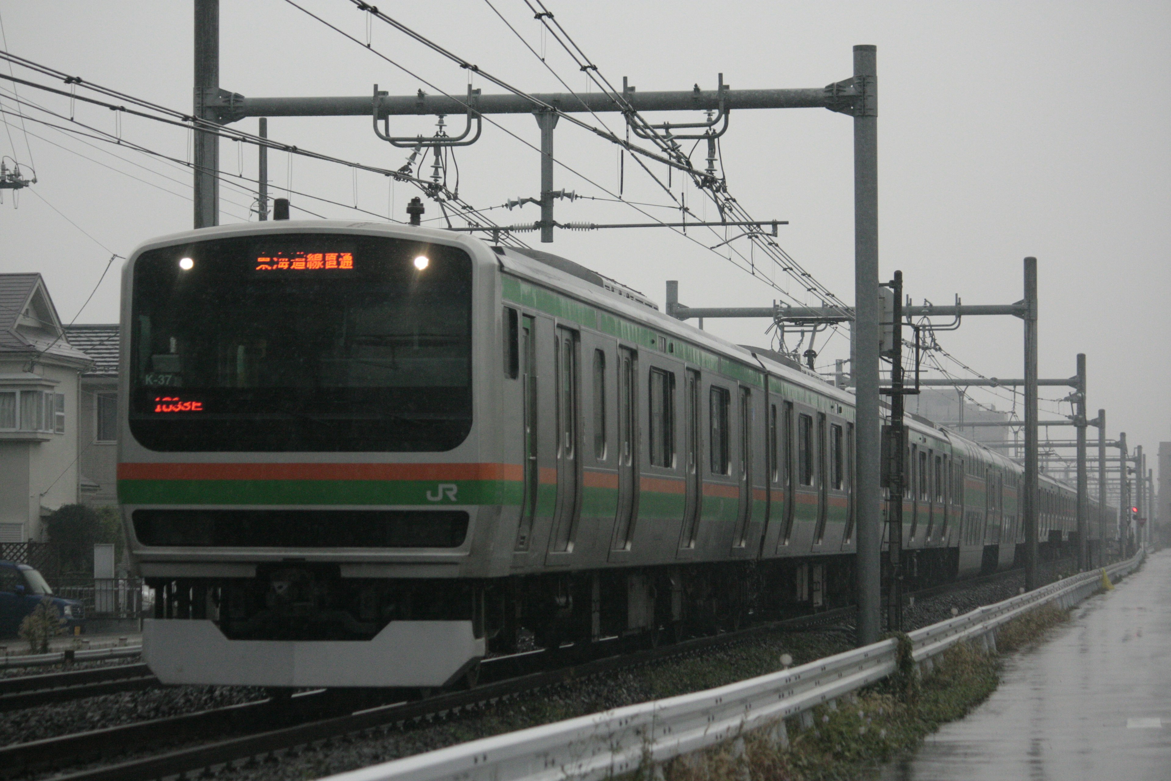 Tren verde corriendo bajo la lluvia con paisaje ferroviario