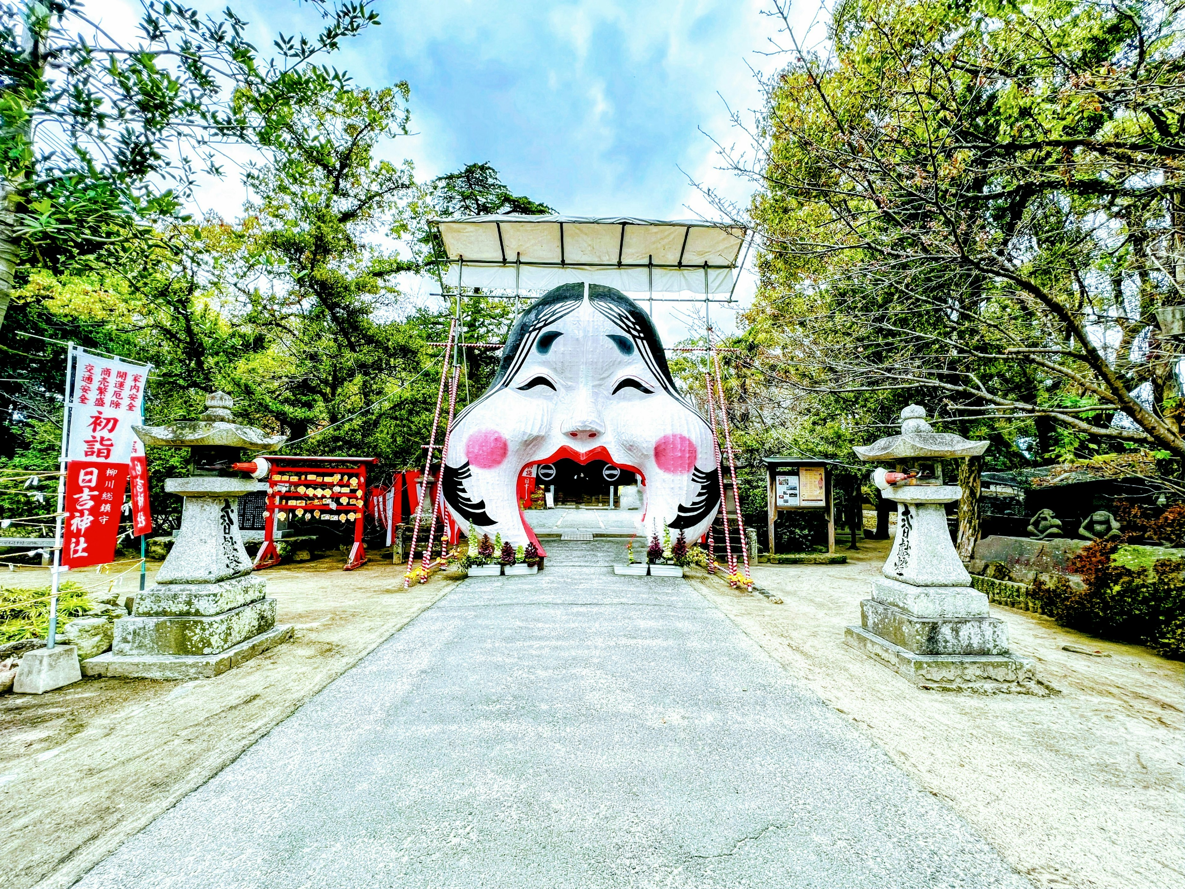 Entrance of a shrine featuring a large face with red cheeks and a blue sky