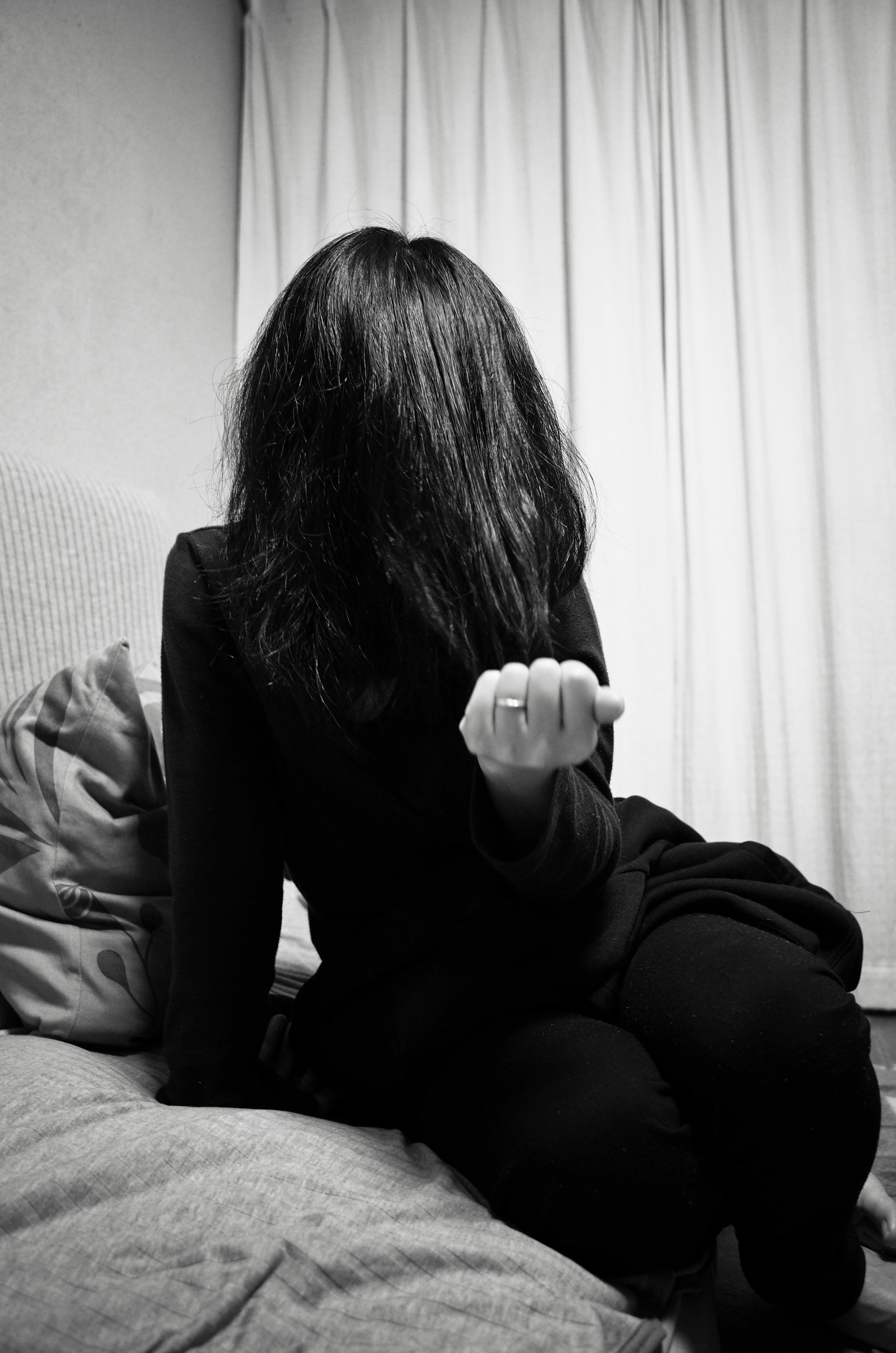 A woman with her face hidden by hair sitting in black clothing