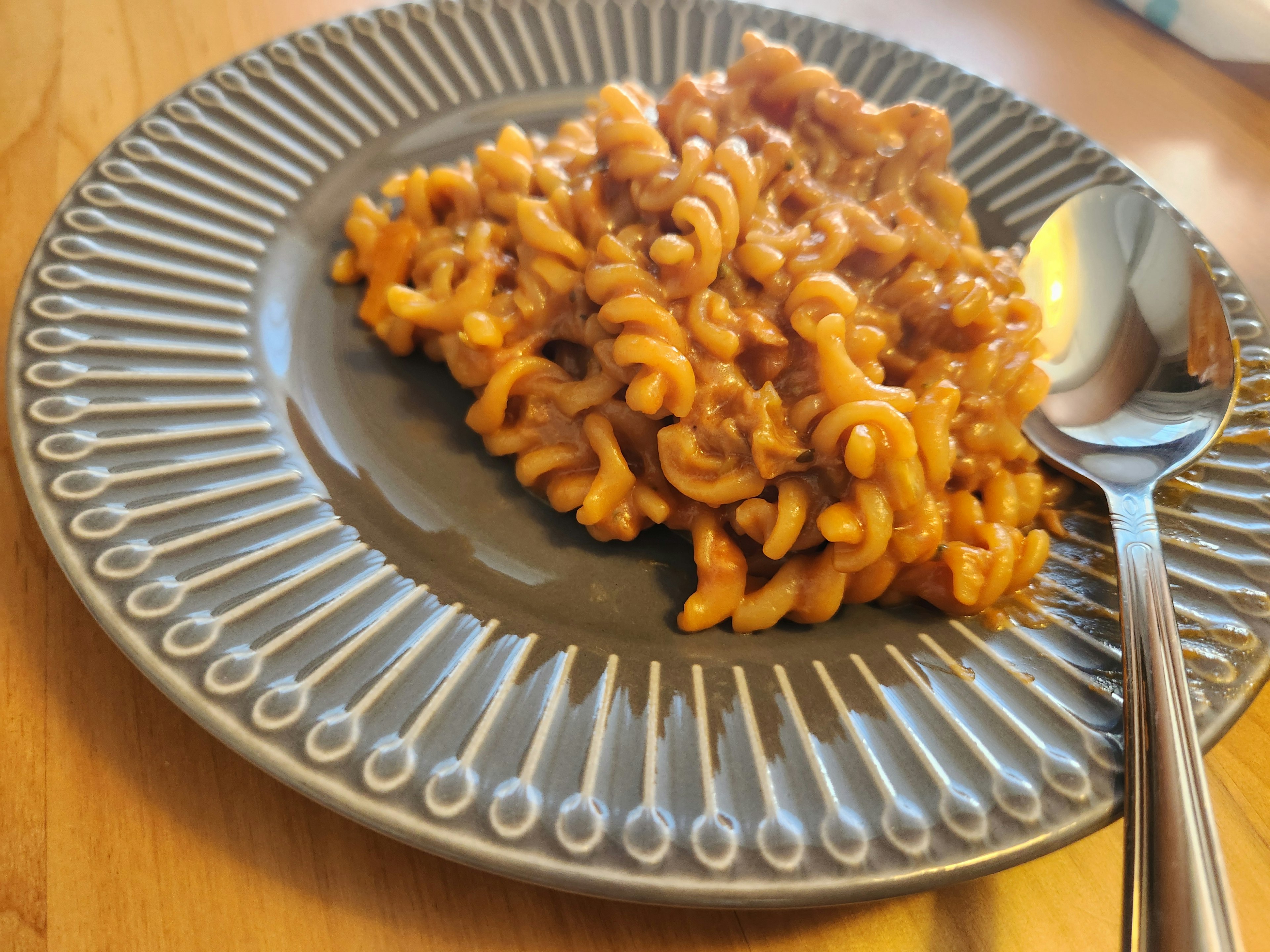 Pasta en espiral servida en un plato decorativo con una cuchara