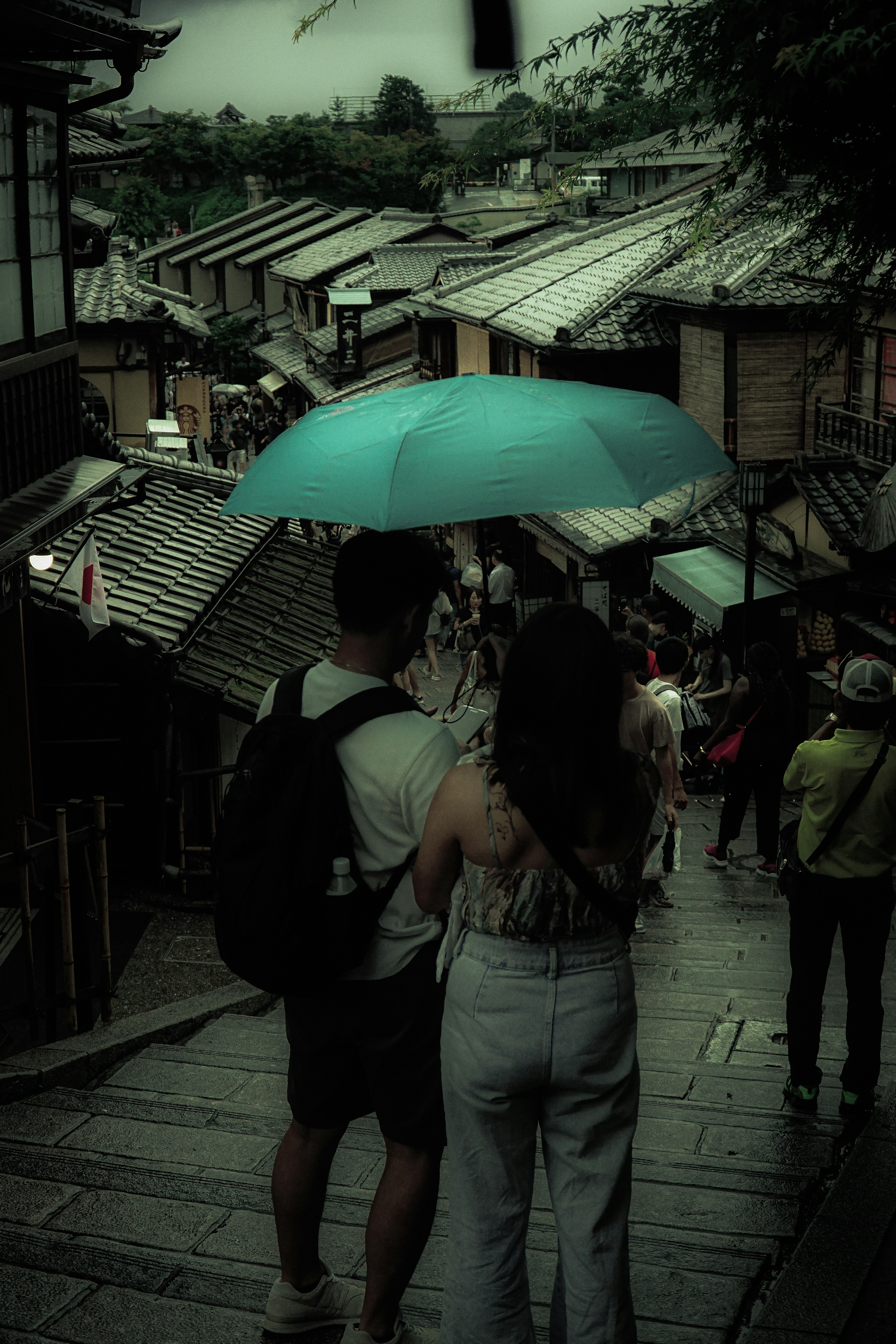 雨傘を持つカップルが古い町並みを歩いている