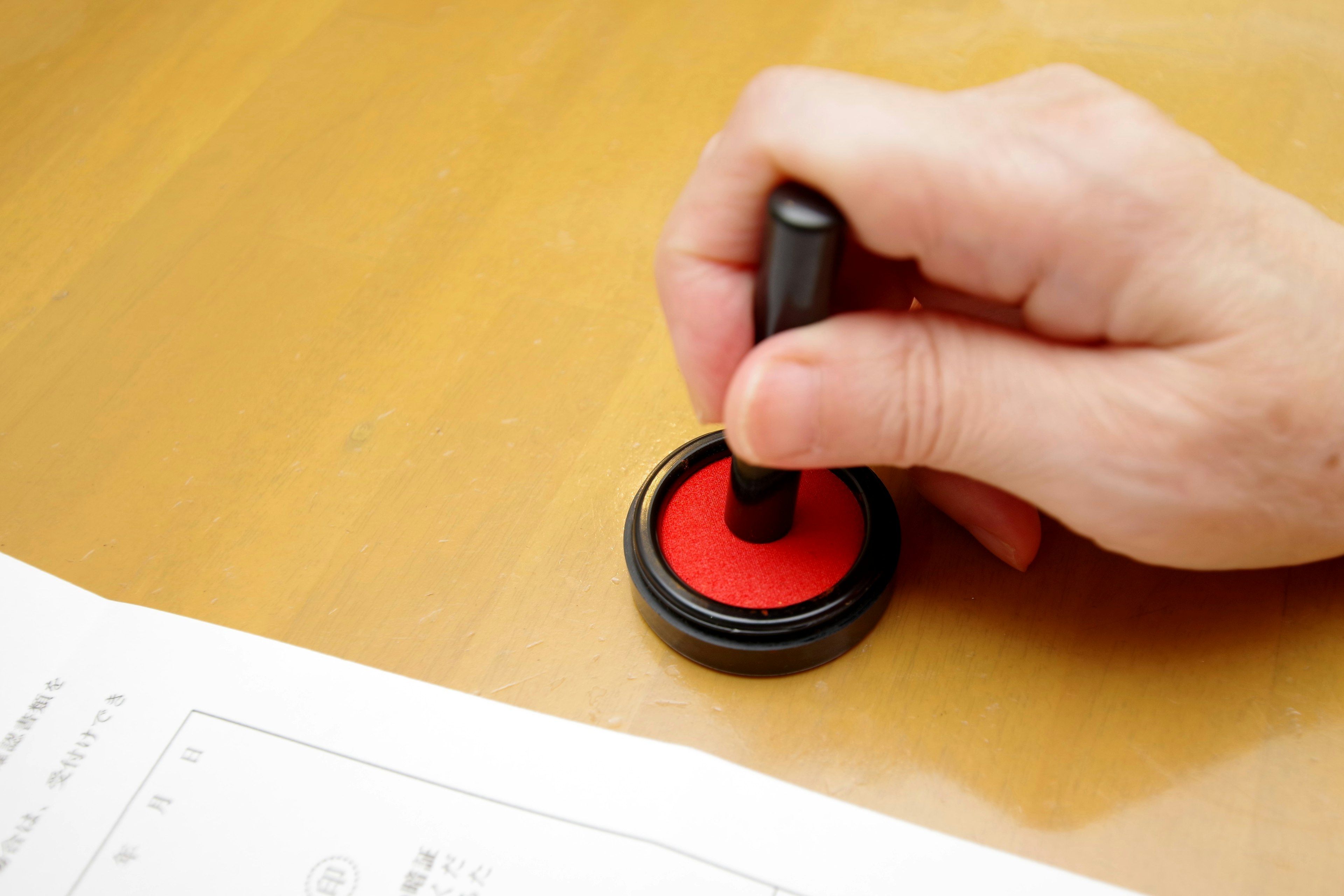 Hand pressing a red stamp onto paper