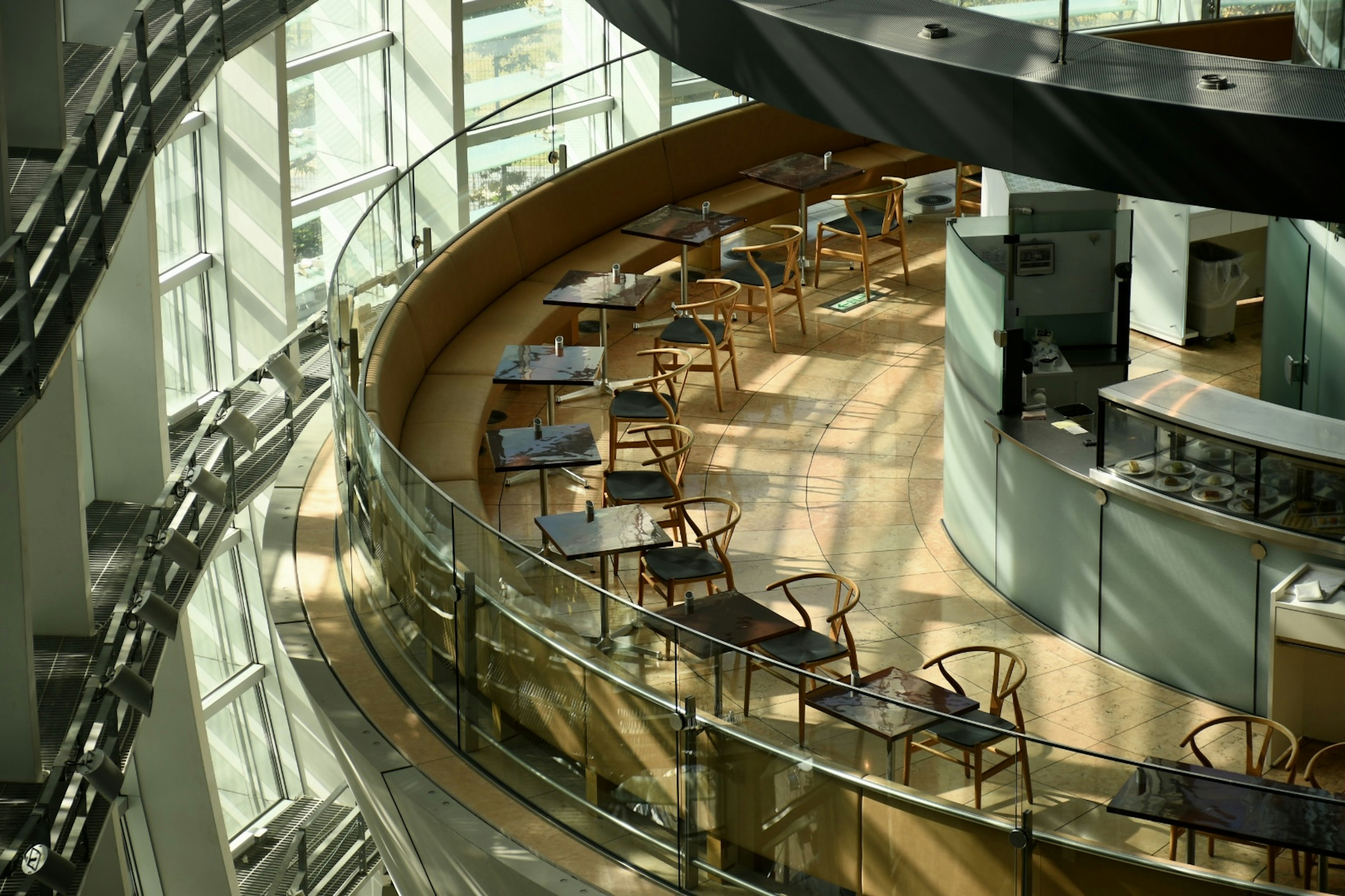 Interior of a cafe with bright glass walls curved tables and chairs arranged