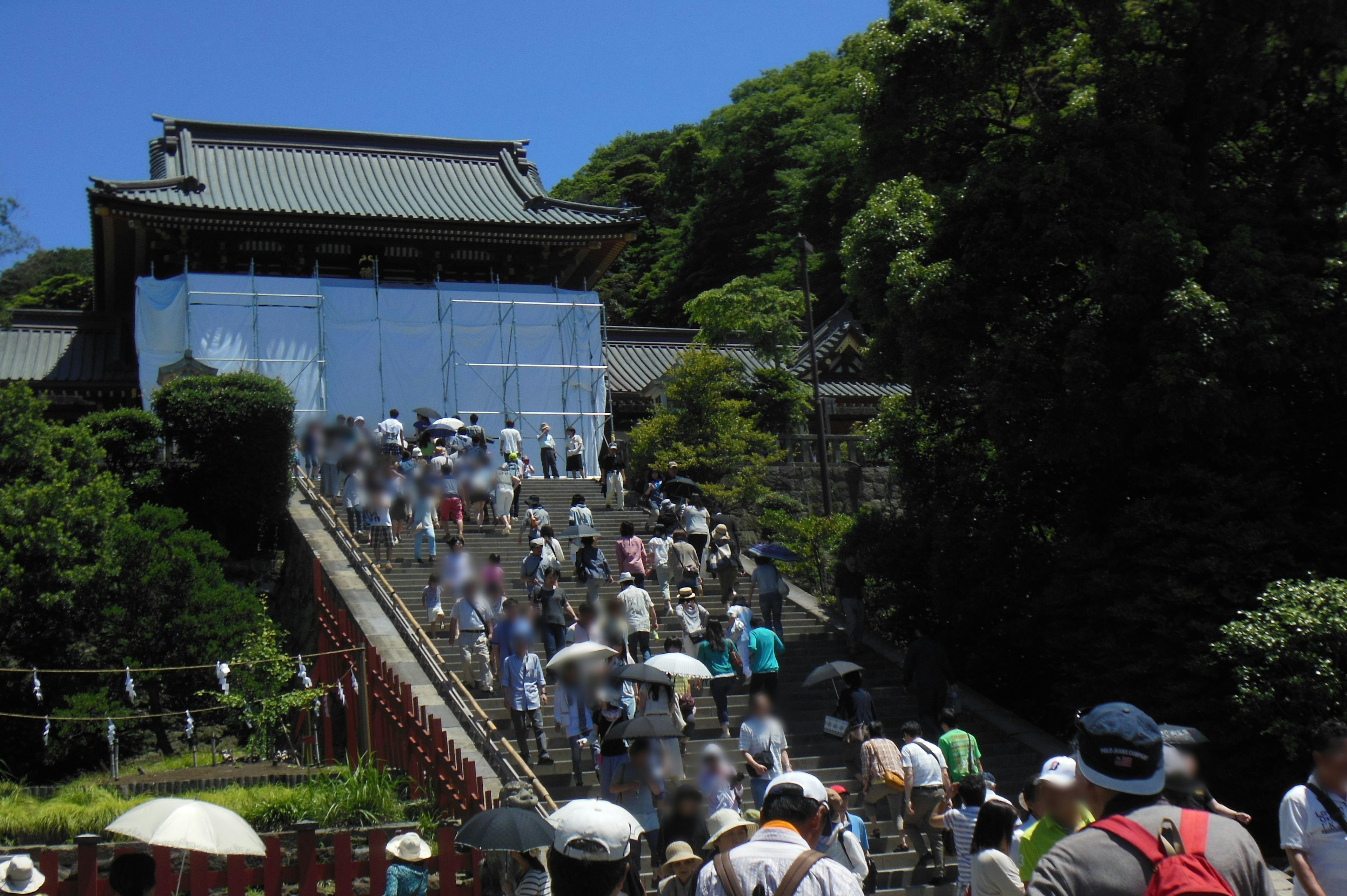 多くの人々が階段を上っている神社の画像，青い空と緑の木々が背景