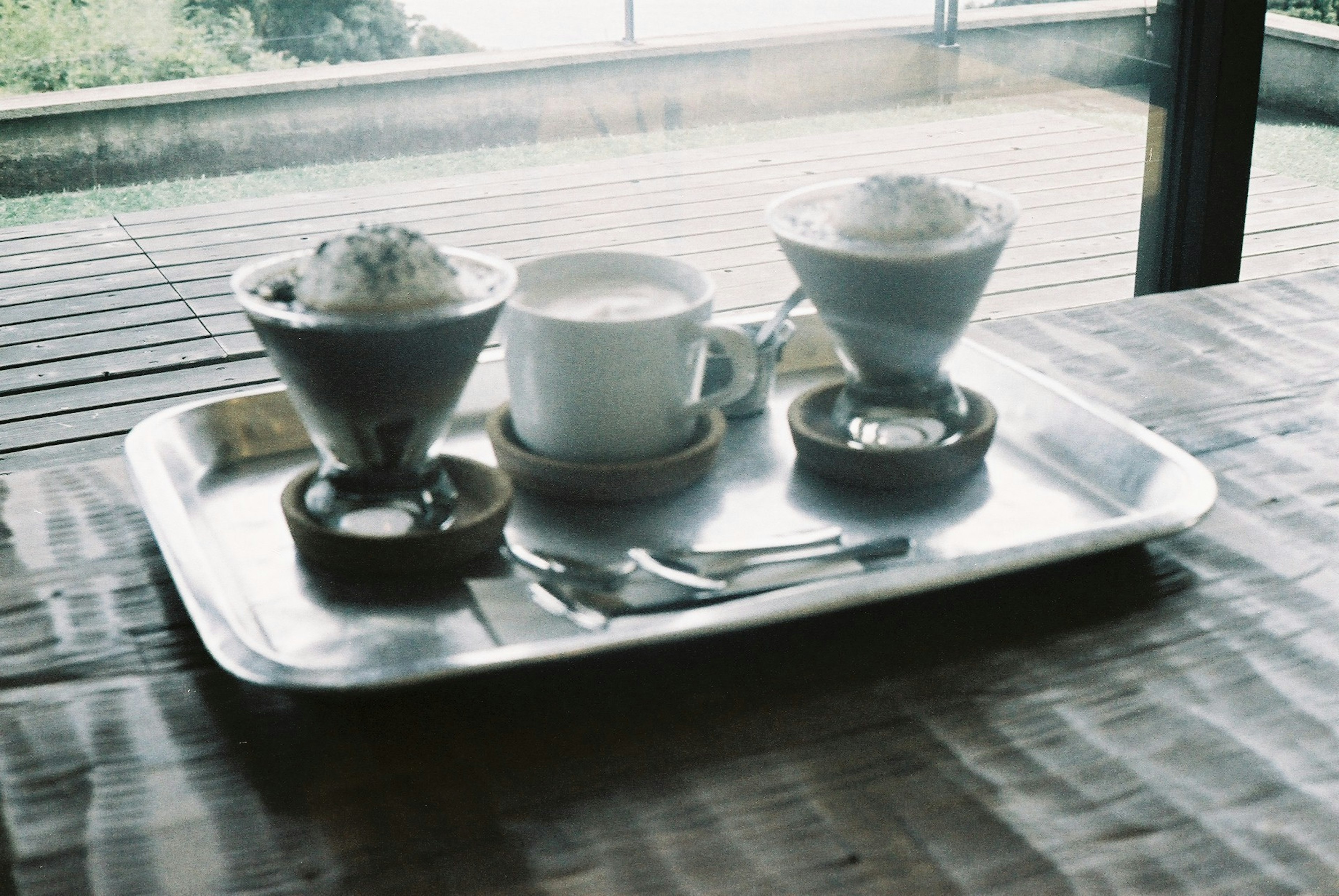 Plateau argenté avec trois tasses de café et un dessert sur une table en bois