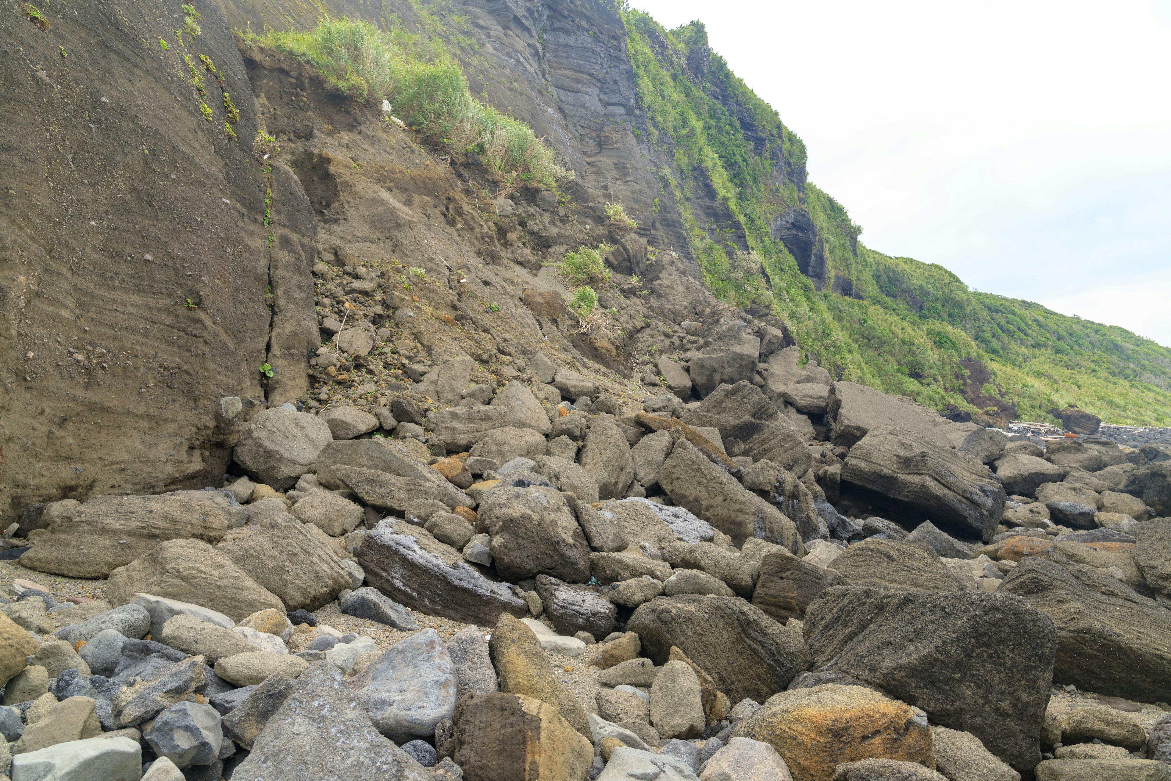 Rocky shoreline with scattered boulders green grass on the cliffs