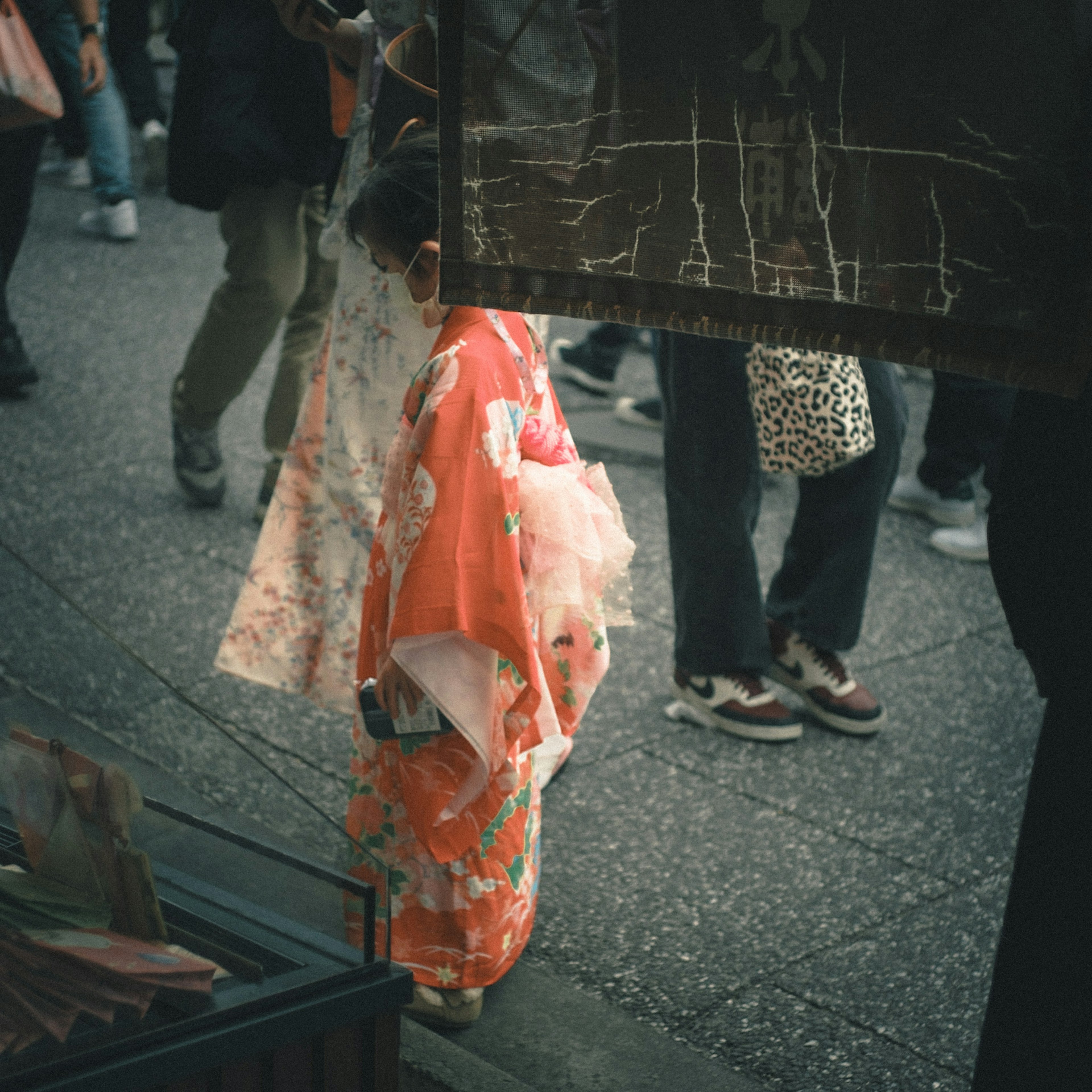 Bambino in kimono tradizionale che cammina per strada circondato da persone e abiti colorati