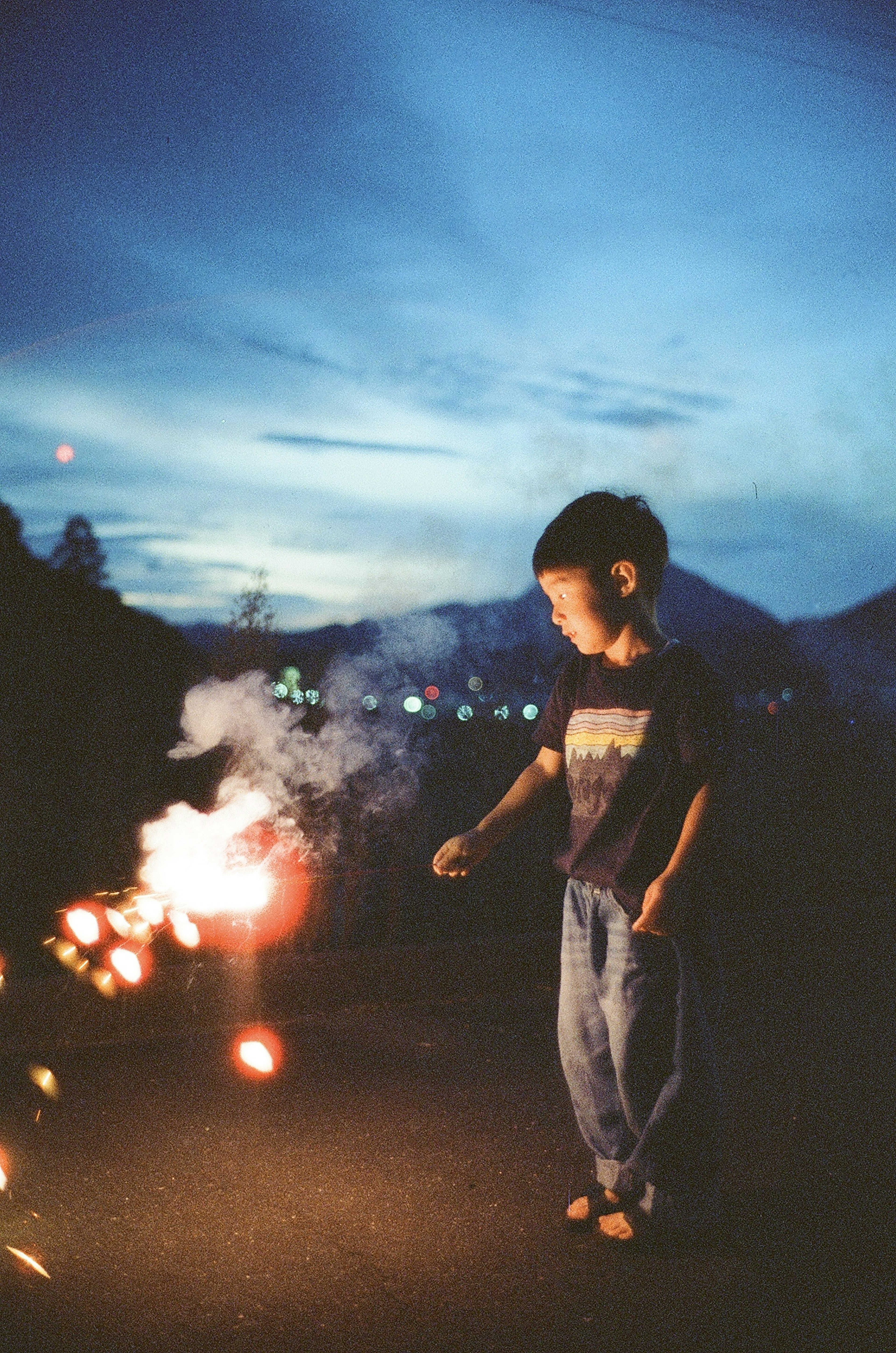 Silhouette d'un enfant tenant un pétard sous le ciel nocturne