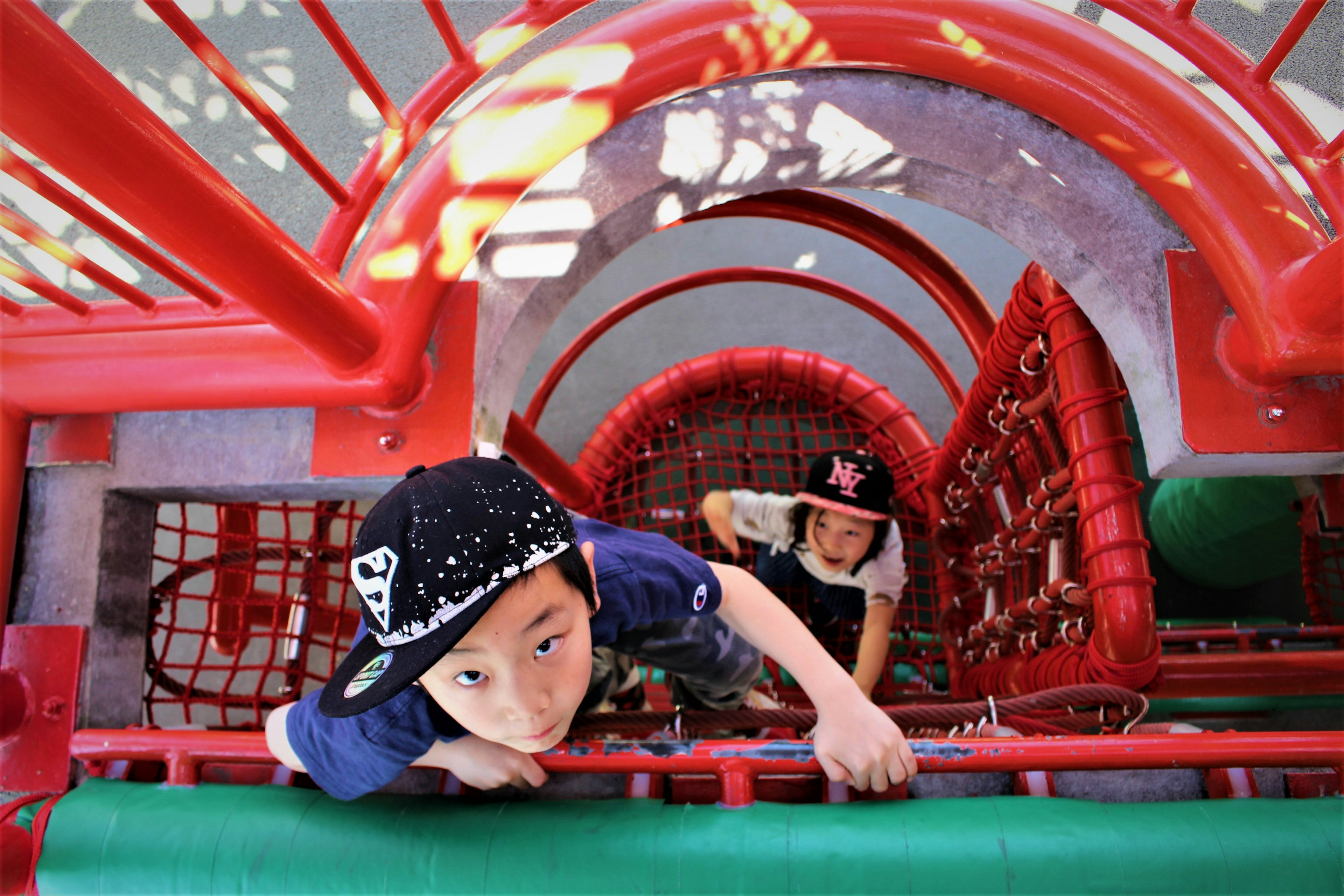 Imagen desde arriba que muestra a niños jugando en un equipo de parque rojo