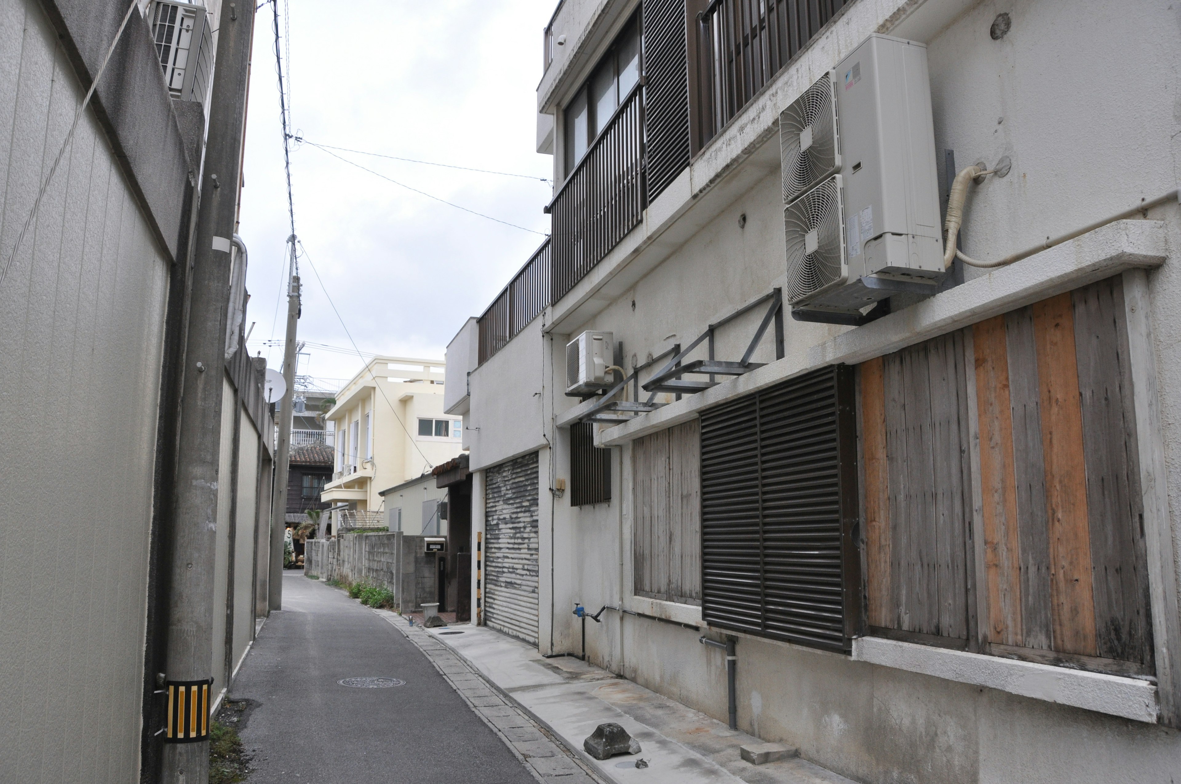 Narrow alley featuring the exterior of an old building with air conditioning units