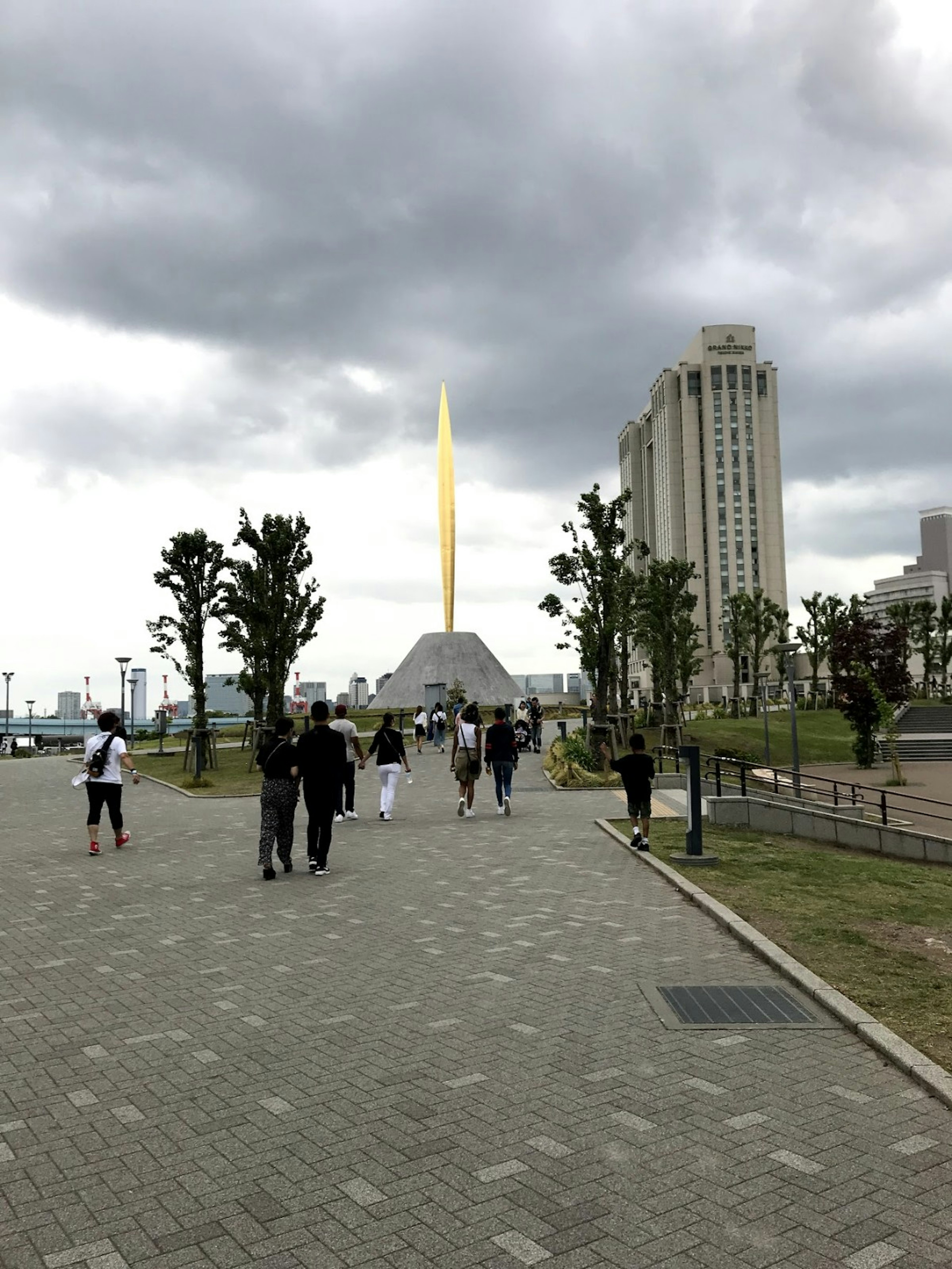 人々が歩いている公園の景色で、金色の塔が目立つ