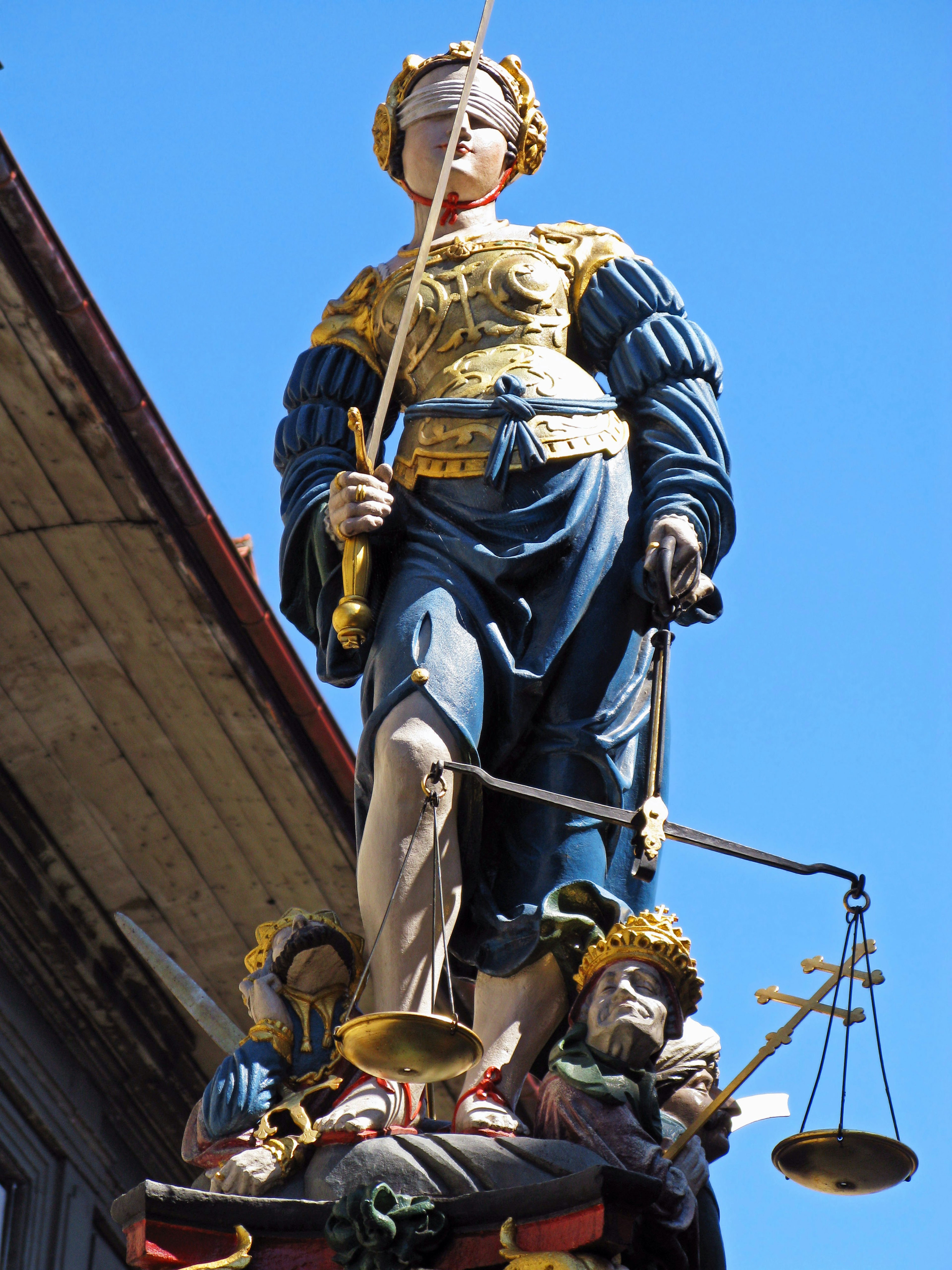 Statue of Lady Justice with golden decorations standing under a blue sky