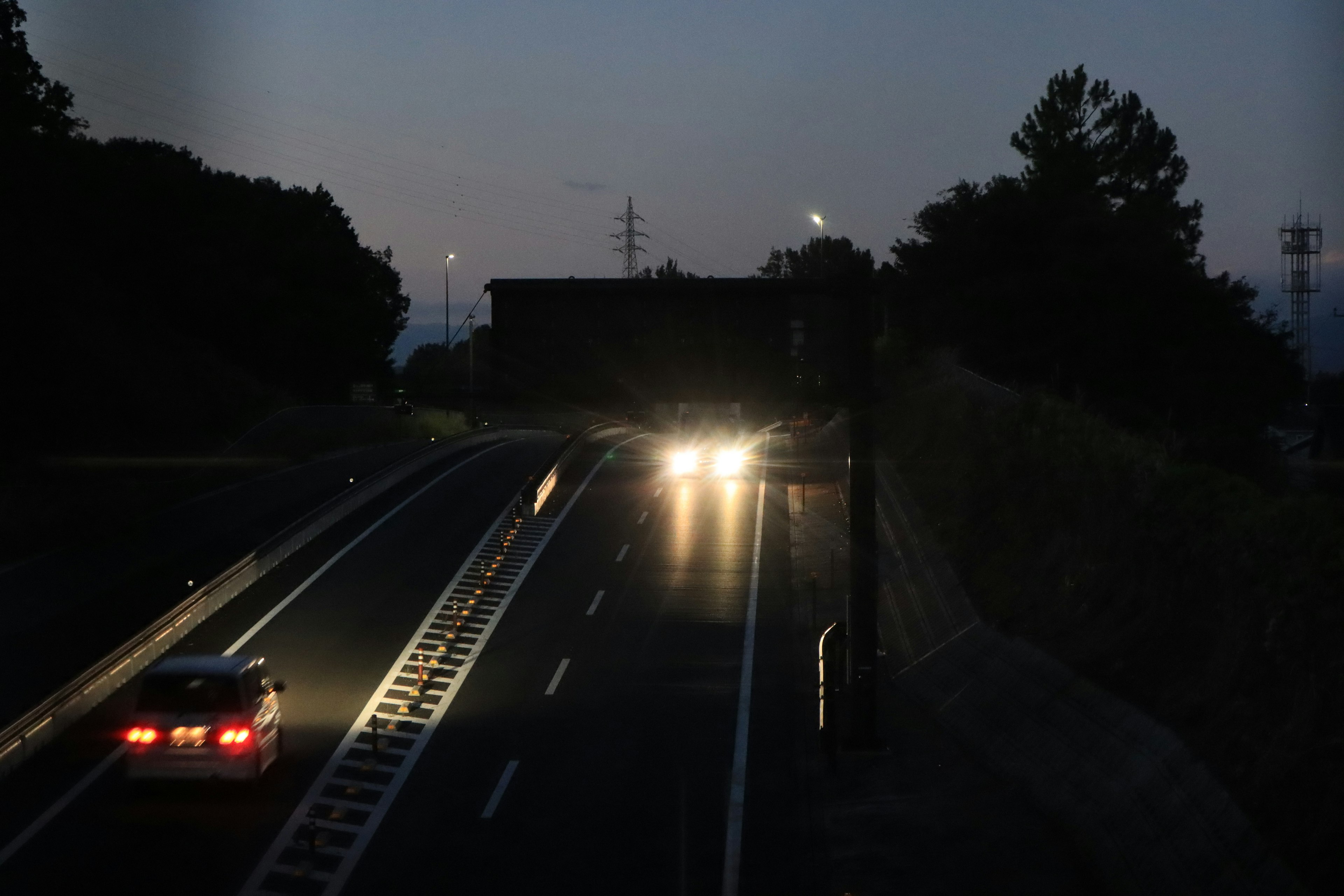 暗い夜の道路を走る車のヘッドライトと街灯の光