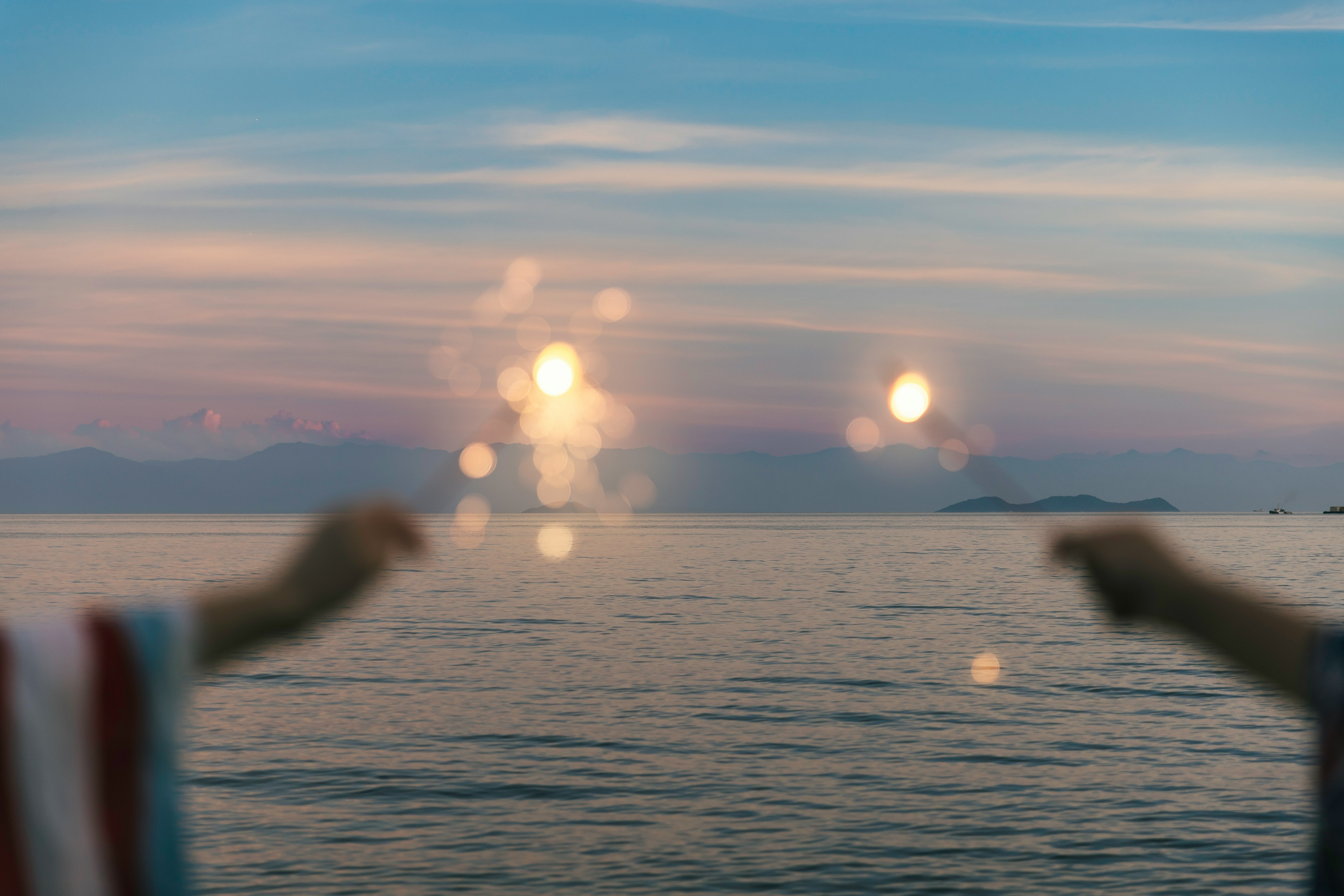 Silhouettes de deux personnes avec les mains tendues contre un océan au coucher du soleil