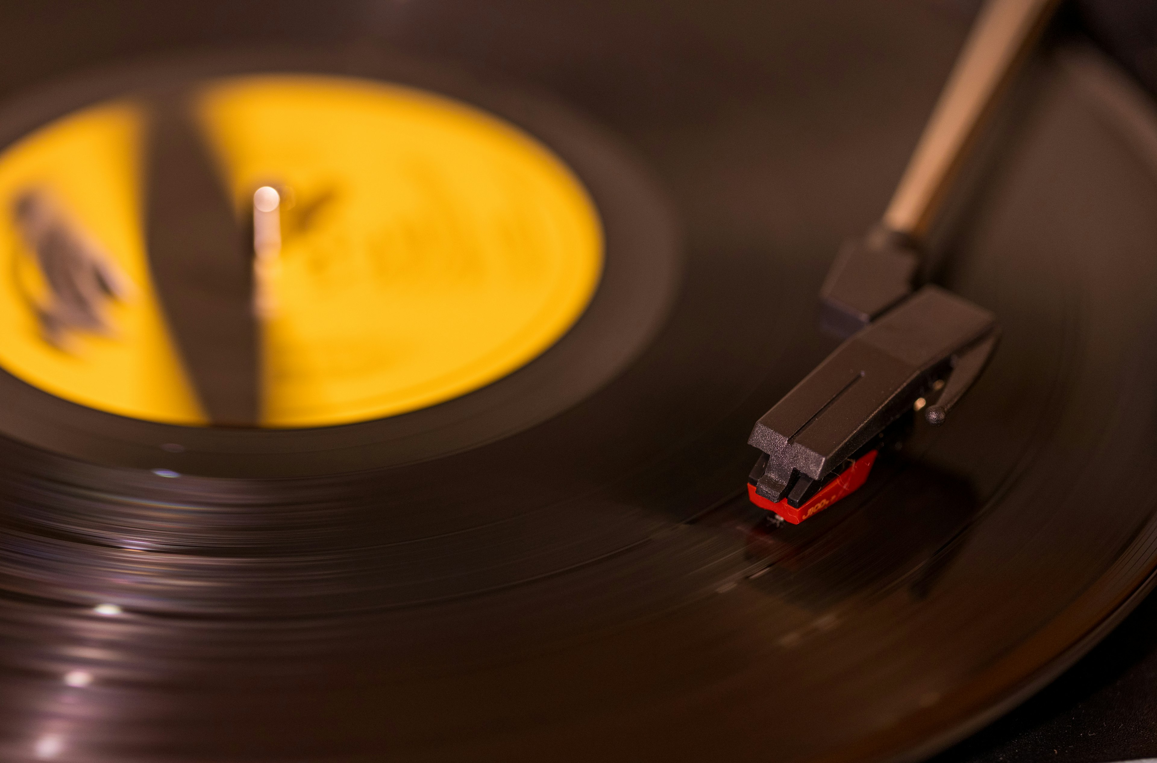 Primo piano di un disco in vinile nero con etichetta gialla su un giradischi