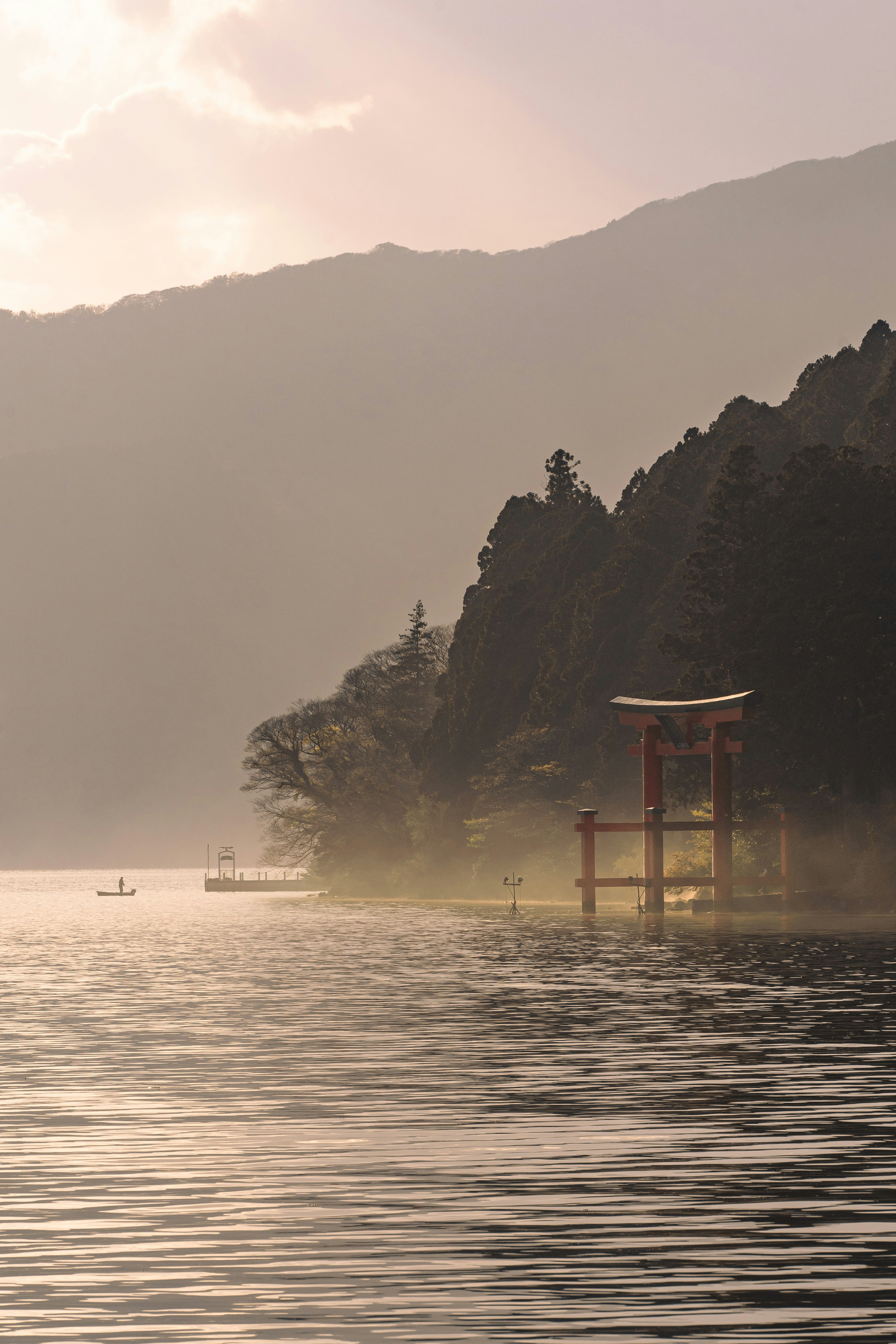 A red torii gate near a lake with a mountainous background