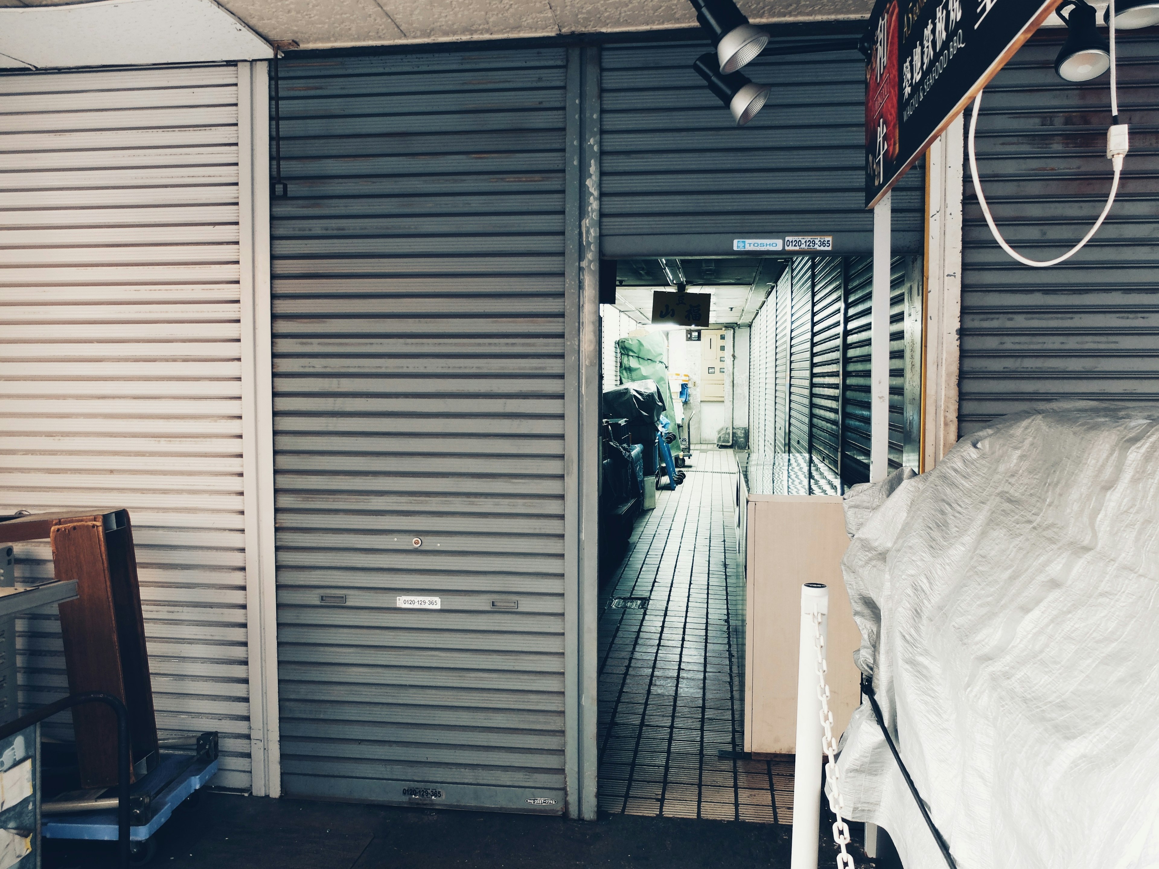 Image of a narrow passageway leading to a closed shop with shutters