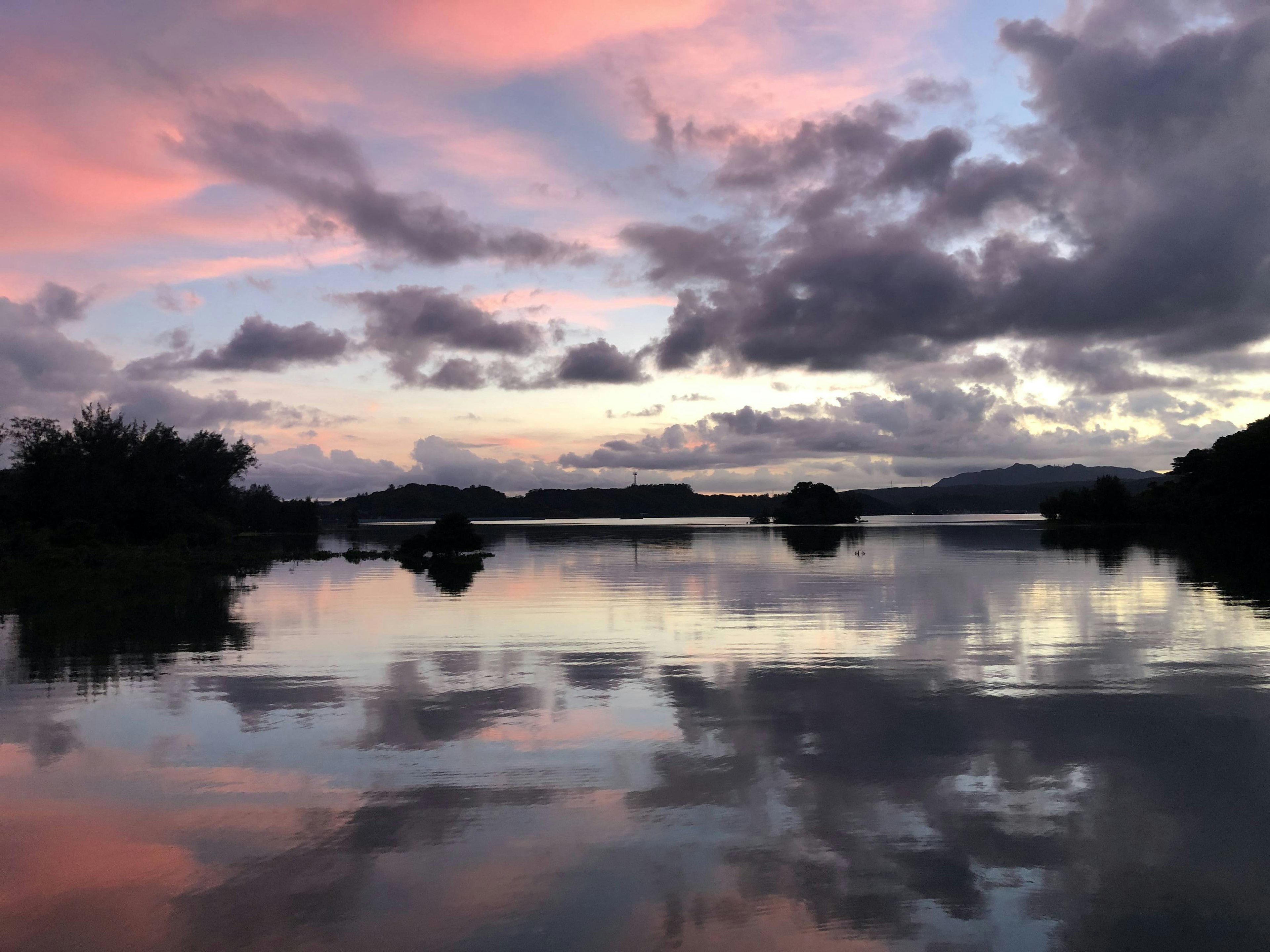 Ruhiger See, der einen schönen Sonnenuntergangshimmel und Wolken reflektiert