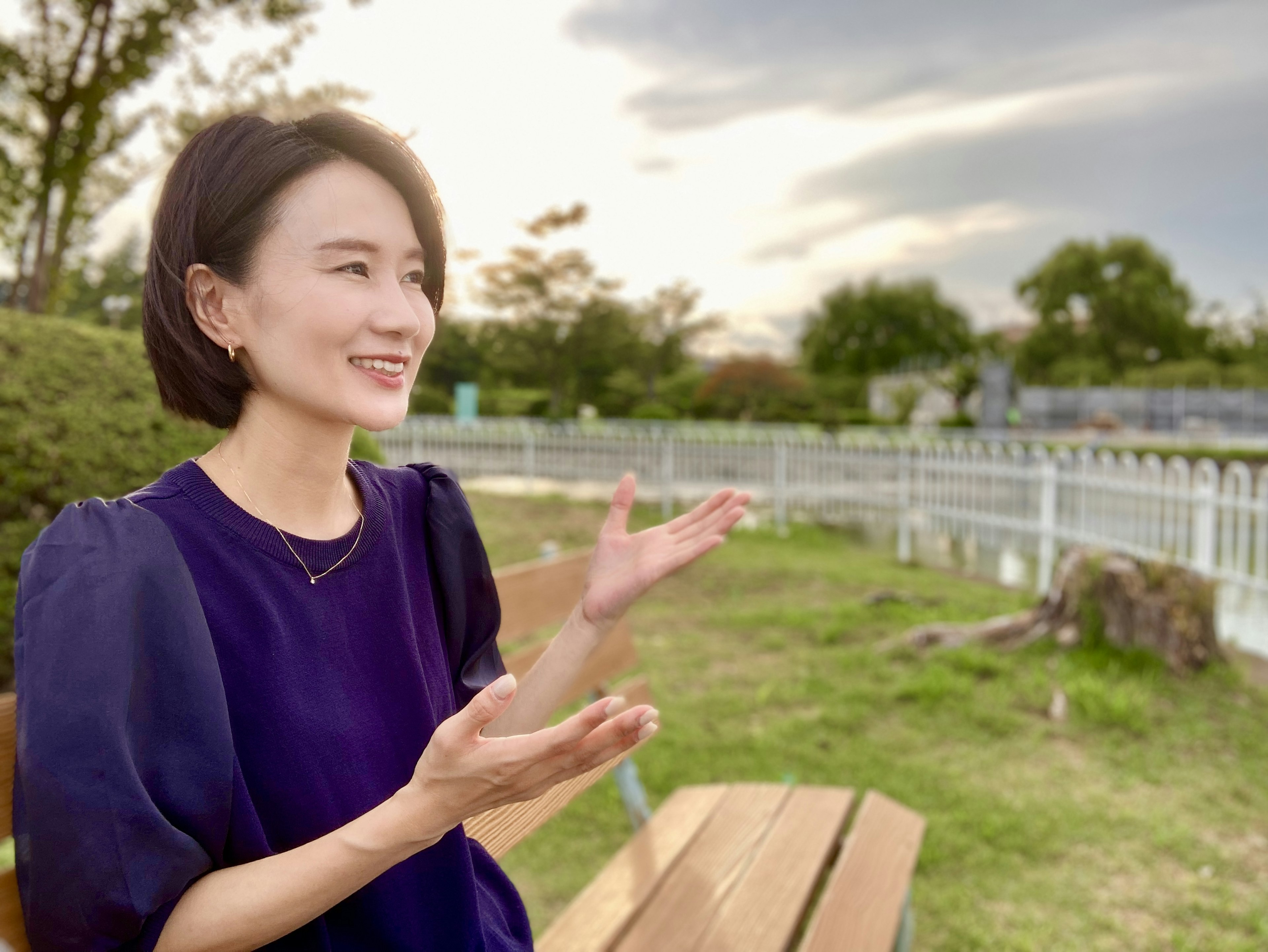 Mujer hablando en un parque con un fondo de cielo y vegetación