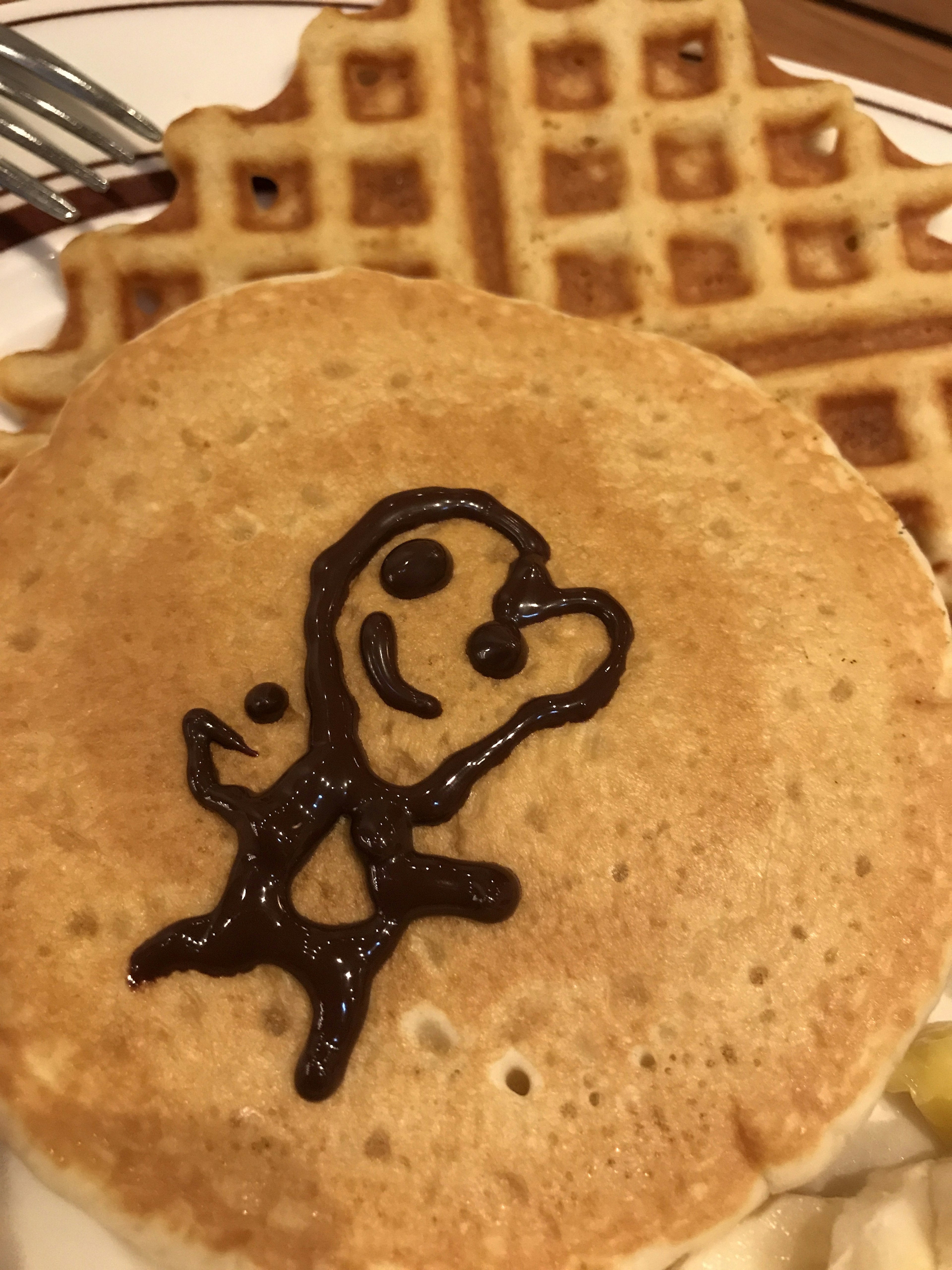 Un diseño de personaje sonriente sobre un pancake con una galleta en el fondo