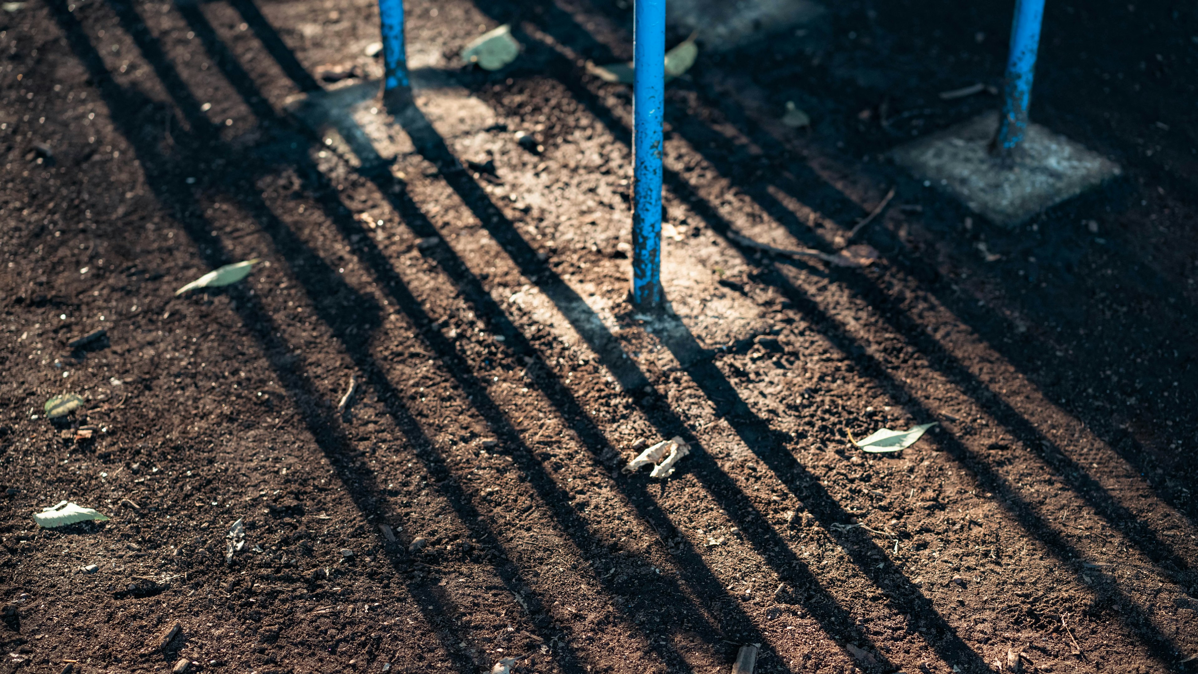 Muster von Schatten, die von blauen Pfosten auf den Boden geworfen werden