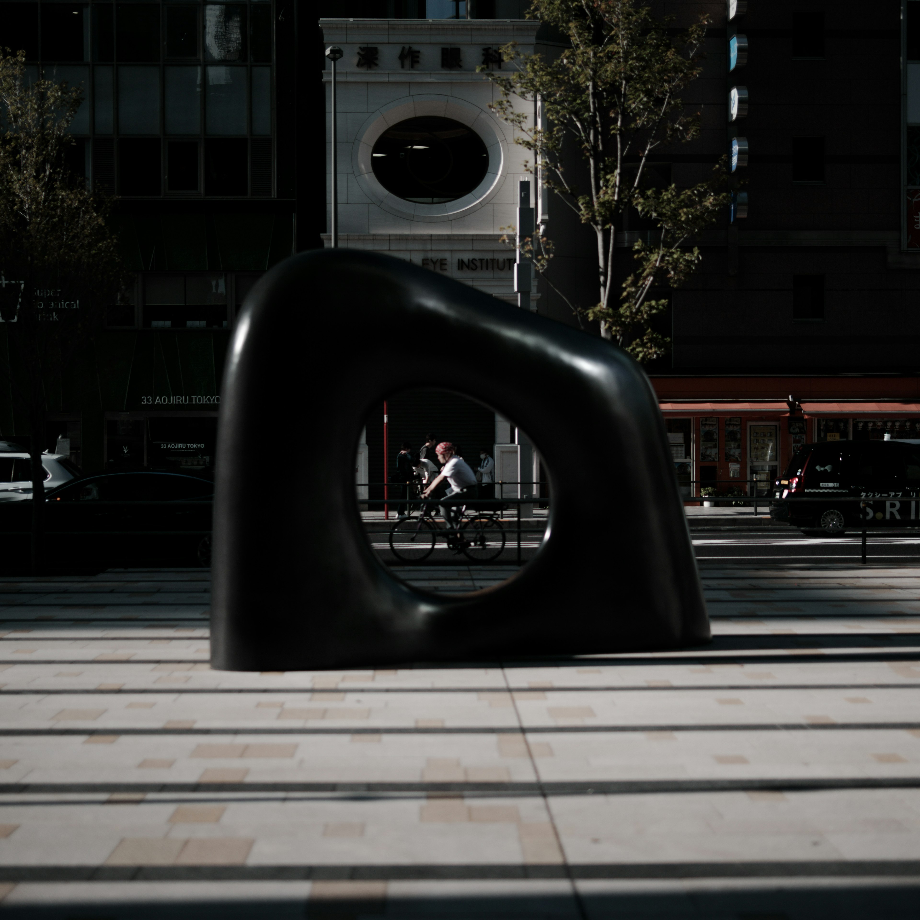 Scultura nera astratta in una piazza con sfondo urbano