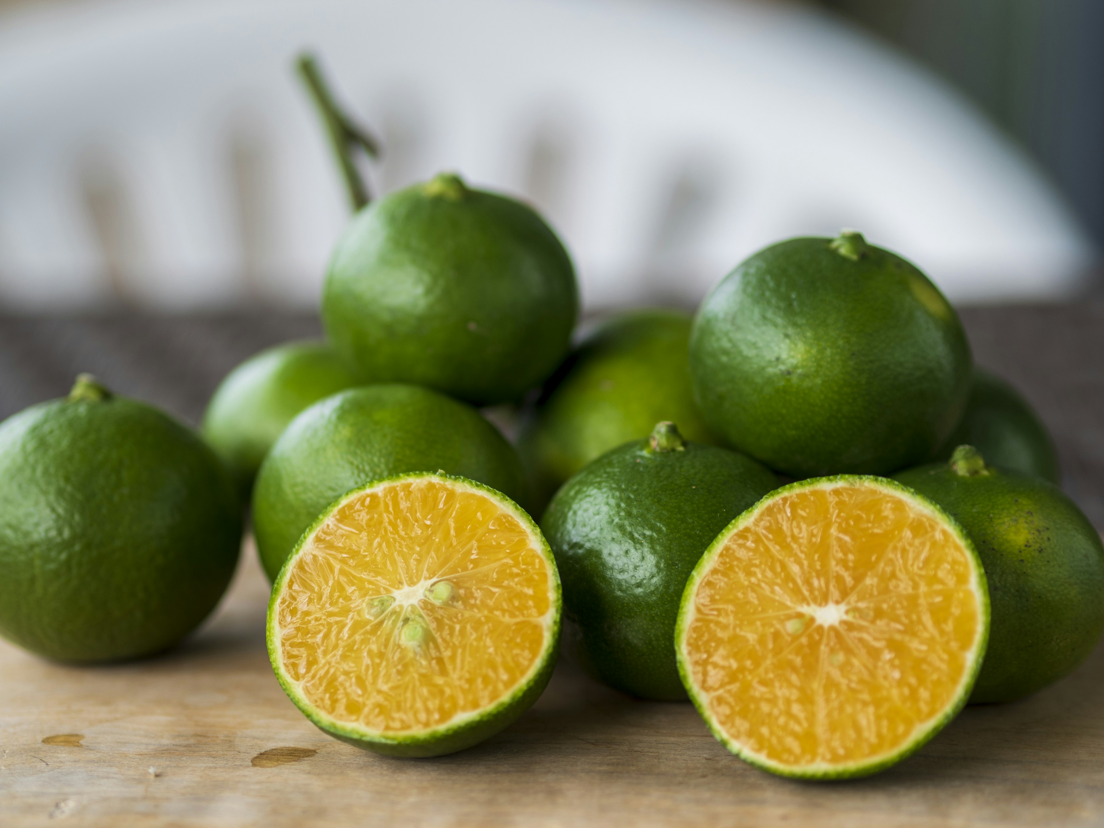 Imagen de naranjas verdes con una naranja cortada que revela su interior