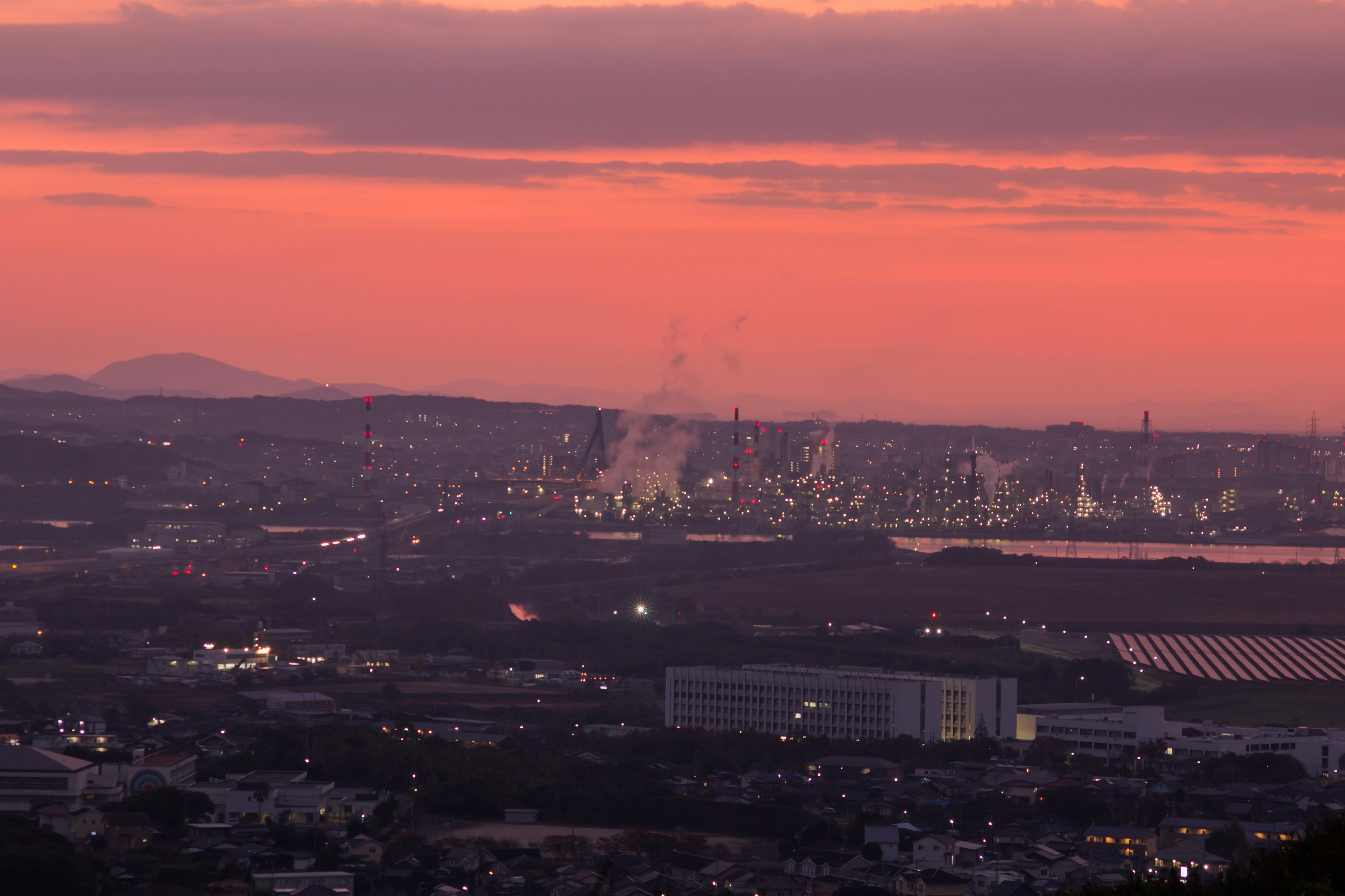 Paesaggio industriale illuminato dal tramonto con fumo