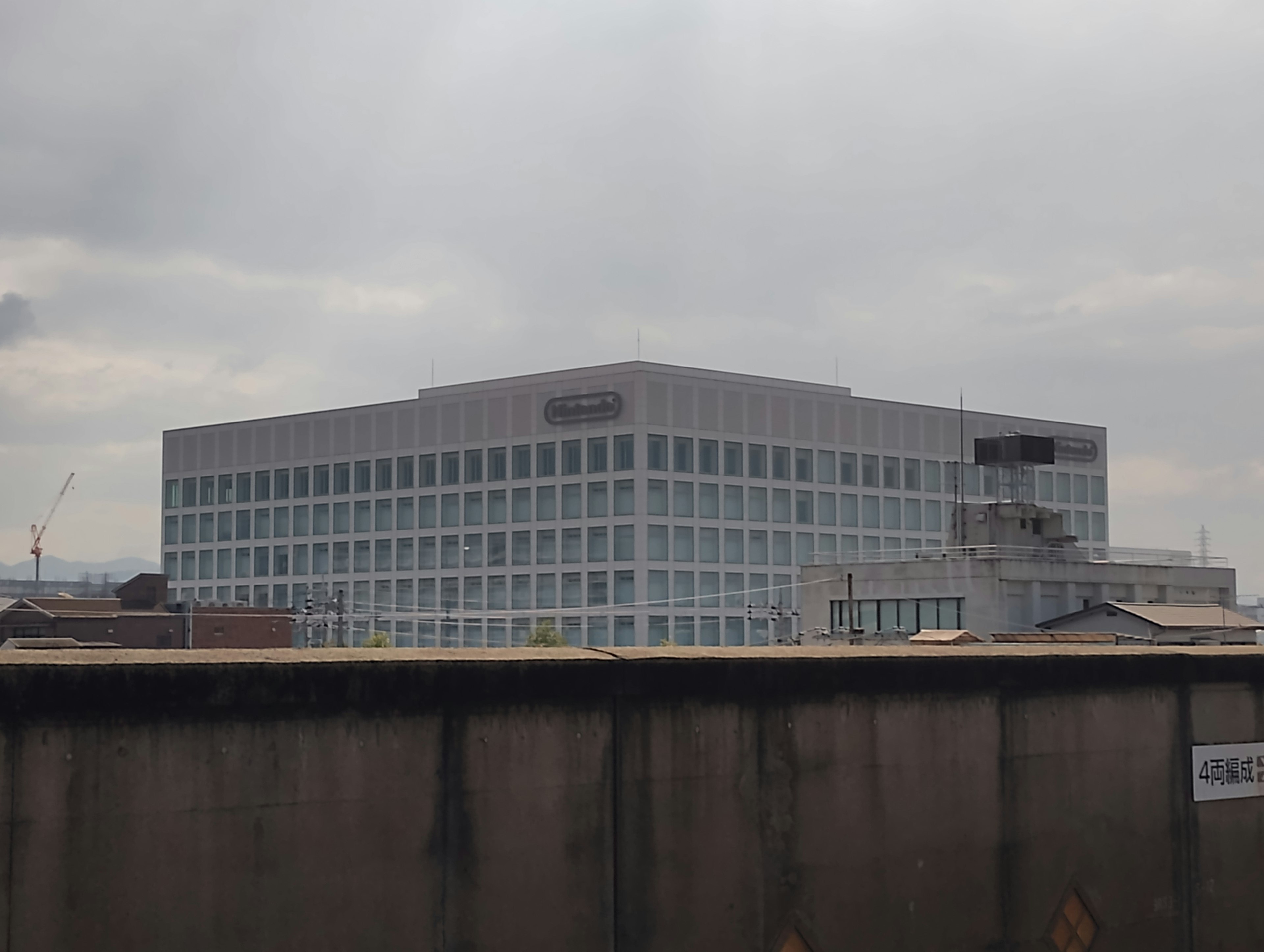 Façade d'un bâtiment de bureaux moderne avec des structures voisines et un chantier visible