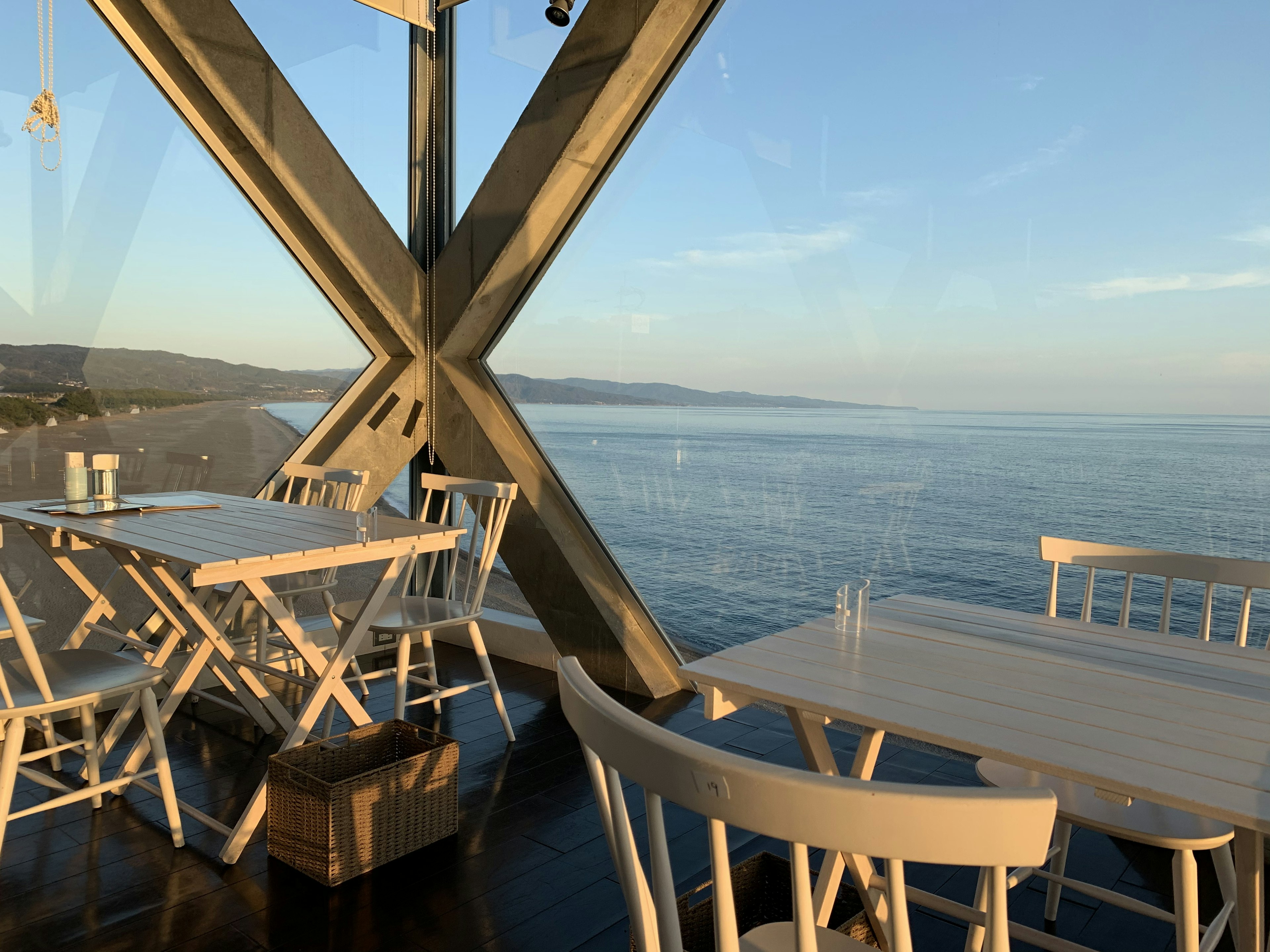 Modern restaurant terrace with white tables and chairs overlooking the sea