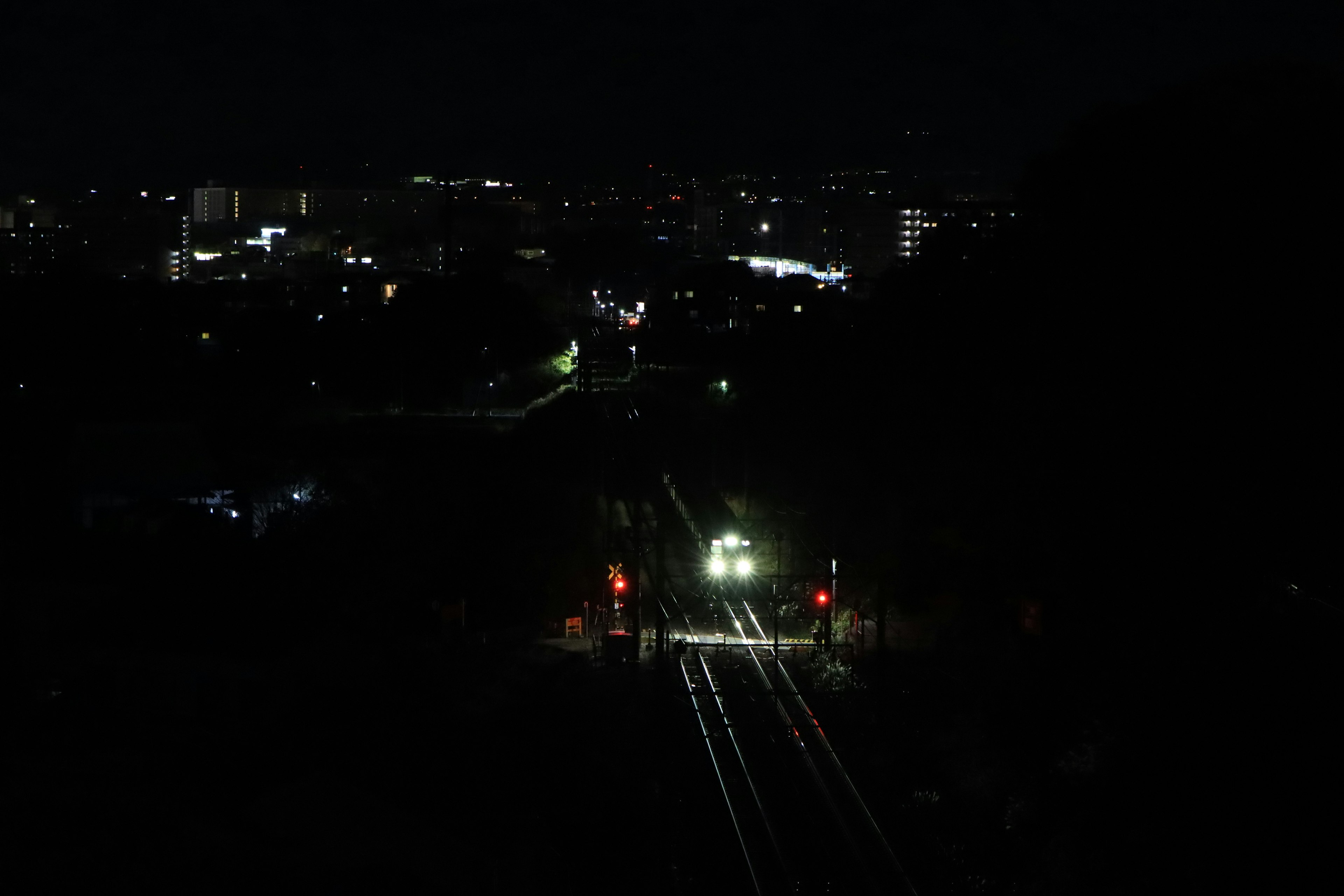 Train tracks illuminated at night with city lights in the background